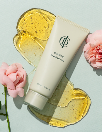 A tube of calming balance gel surrounded by two pieces of gel and pink flowers on a light background.