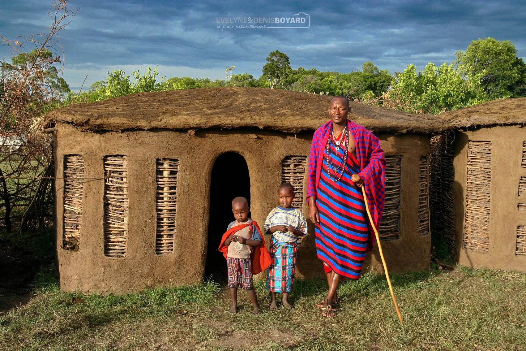 Un massaï avec ses enfants devant leur inkajijik, la case traditionnelle.