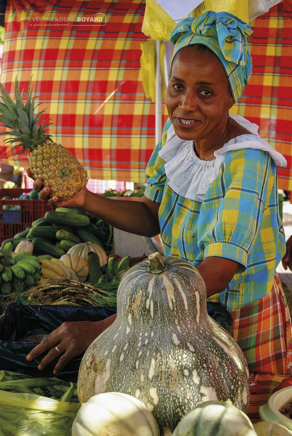 Commerçante en costume madras traditionnel sur un marché en Guadeloupe.
