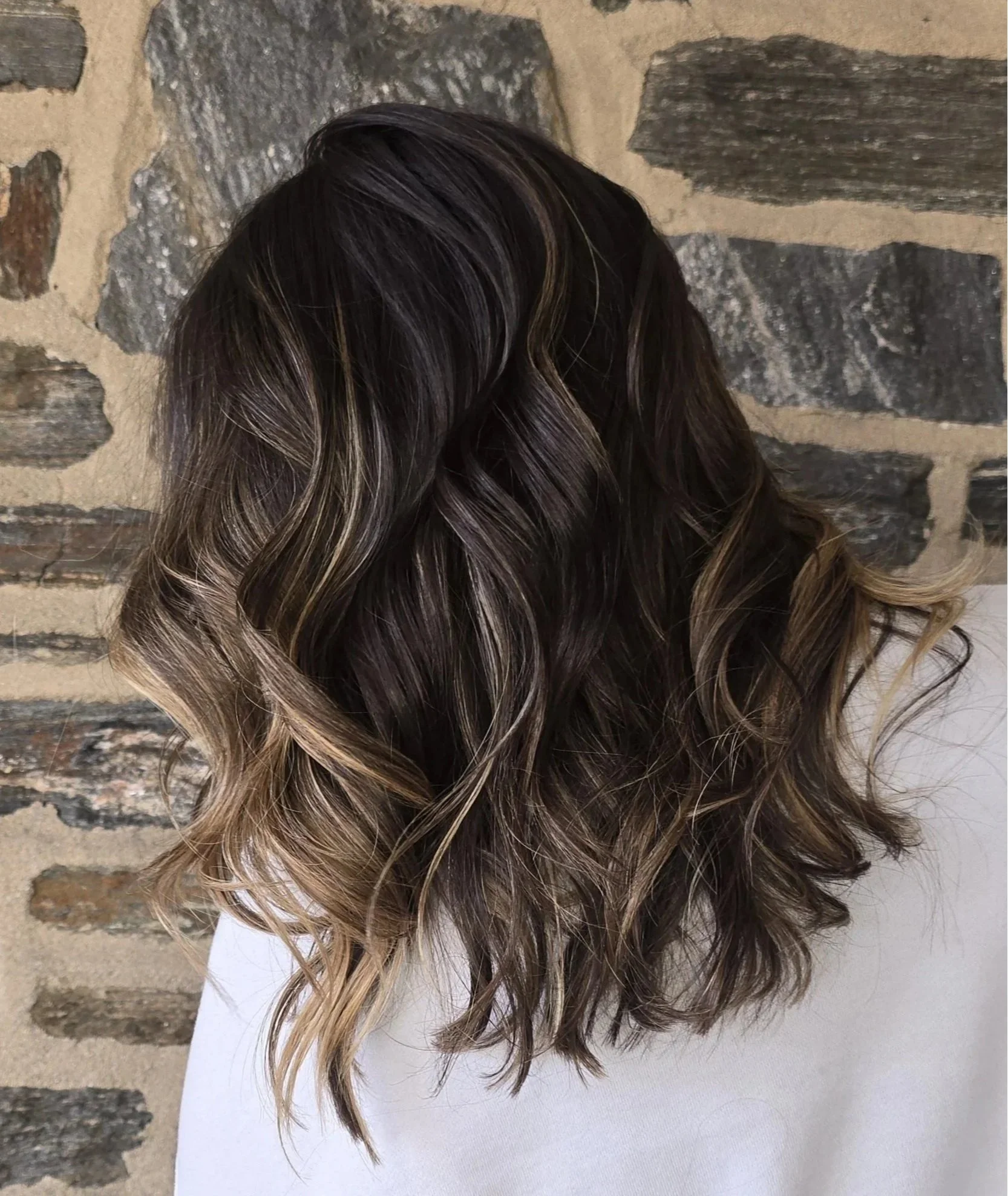 Subtle lived-in highlights with soft beach waves for dimension and low-maintenance brightness.