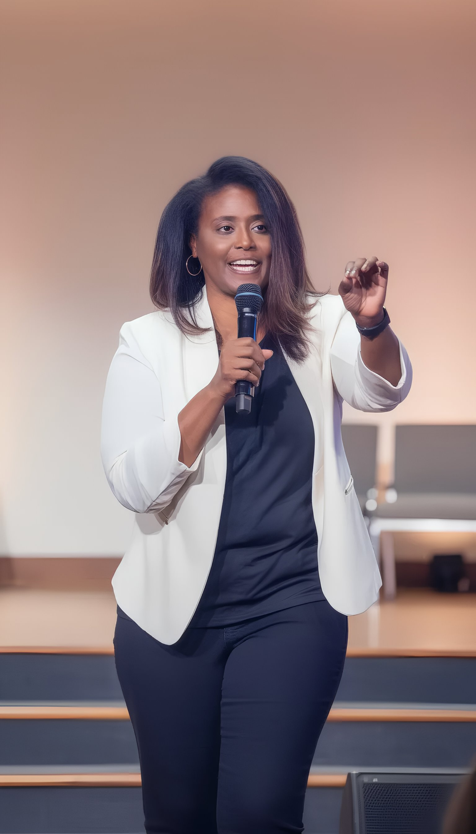Woman speaking at a conference or event, holding a microphone, with a large screen behind her displaying the words 'Seek and Seek' and the name 'Keilee Craig'.