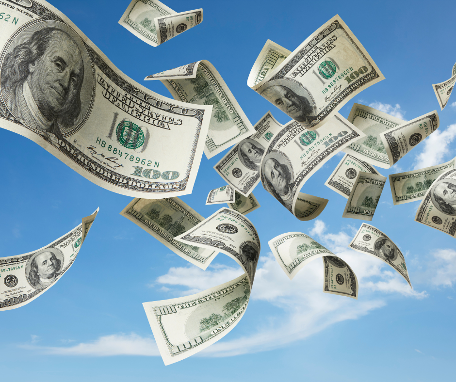 Hundreds of $100 bills flying through a clear blue sky.