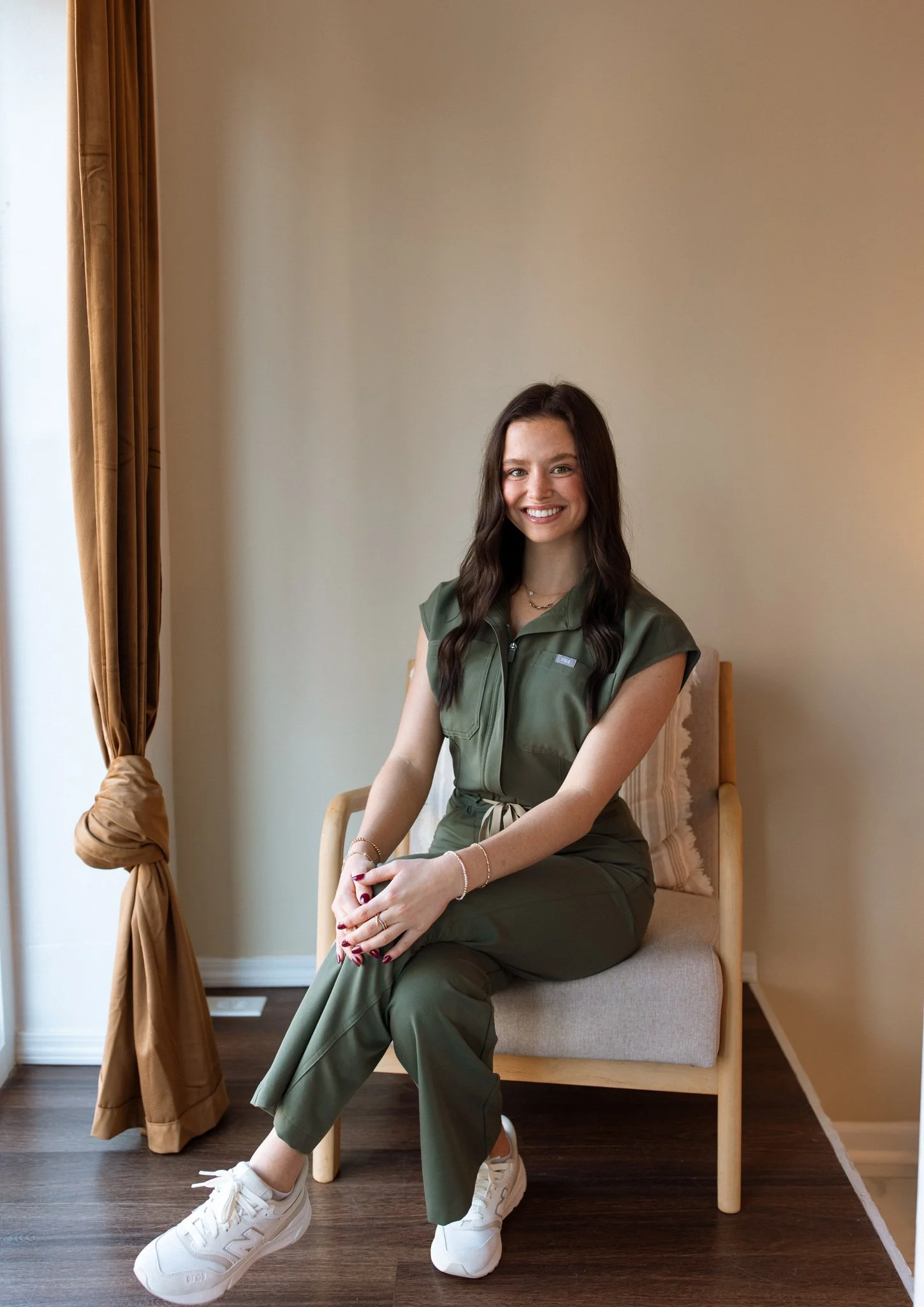 Smiling woman with dark hair in a black outfit against a plain background.