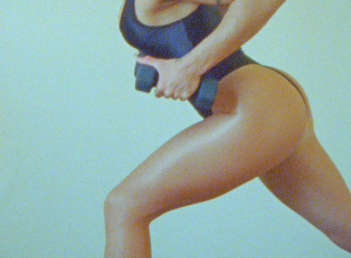 Woman in workout clothes holding a dumbbell while doing lunges.