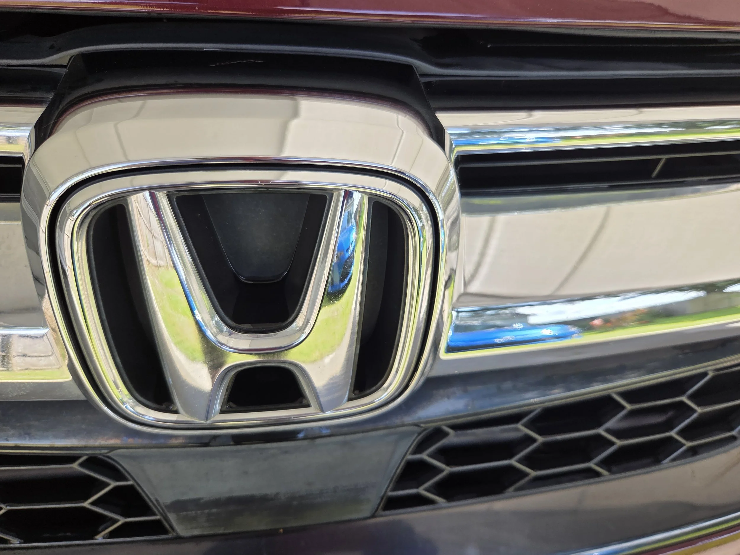 Close-up of a car's front grille and chrome Honda emblem.