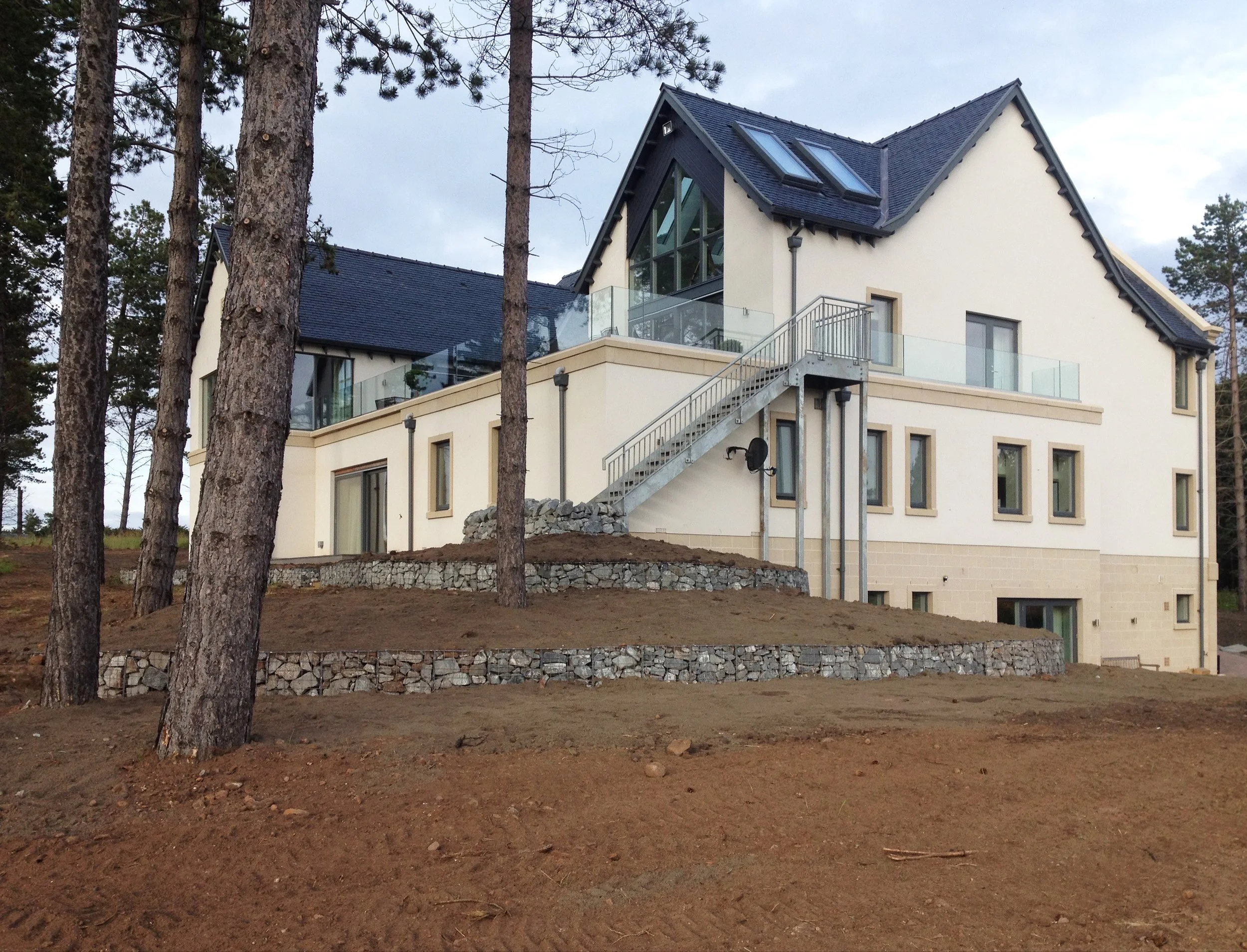 Bare earth surrounding a new build house amongst Pines.