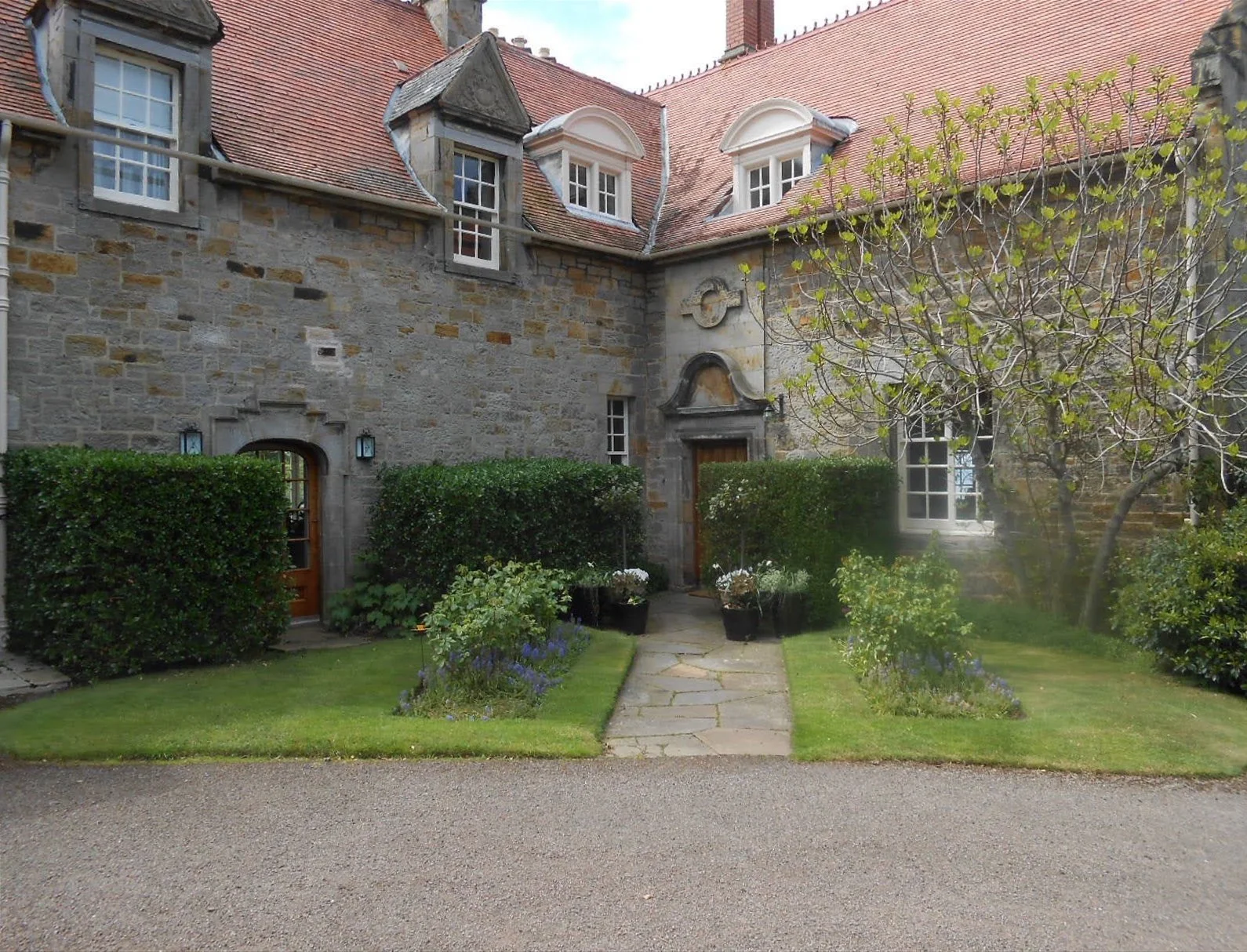 Historic house with lawn, hedging, and Rose beds in front.