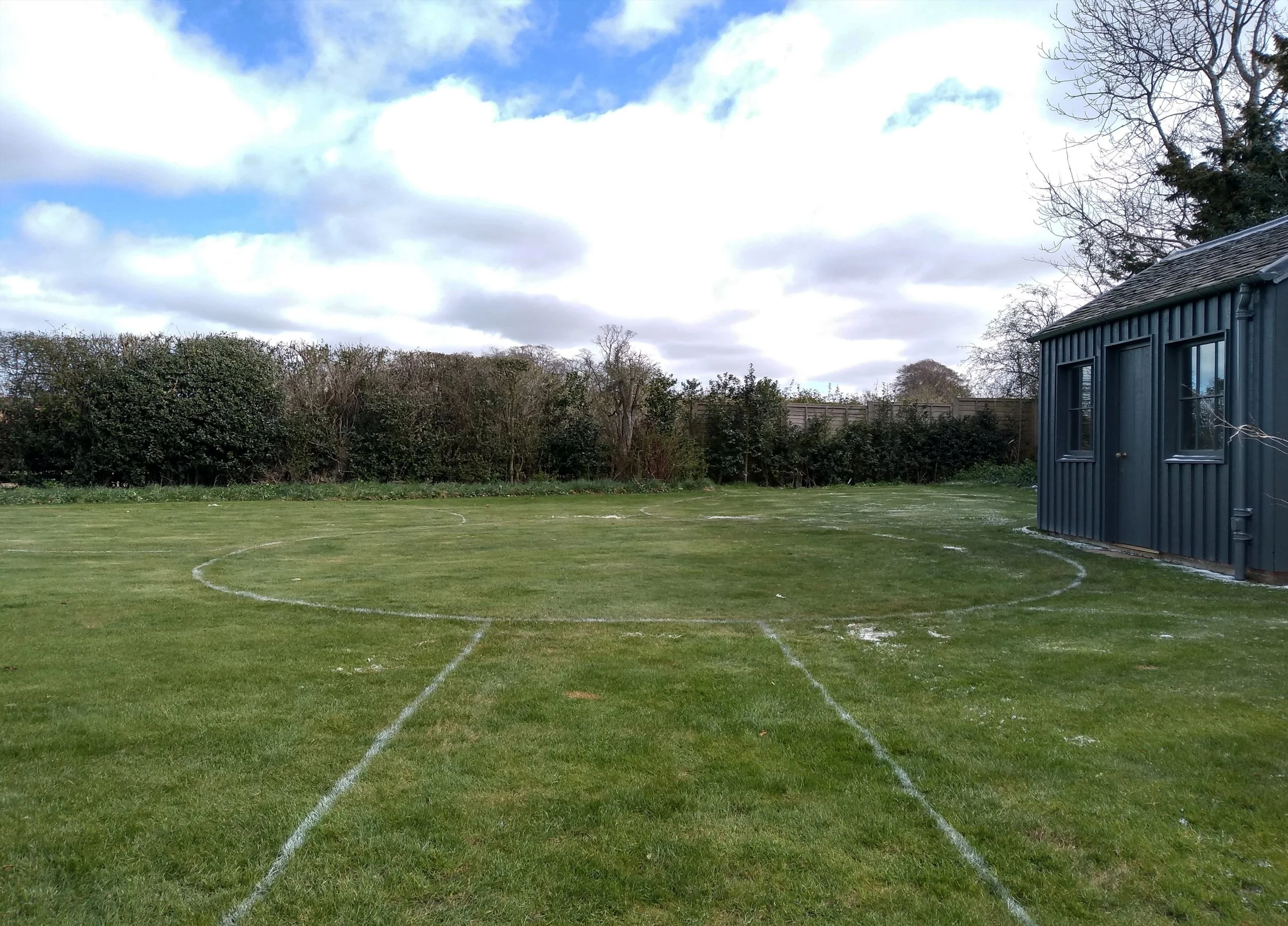 Bare lawn with a design laid out in grass paint ready to be cut.