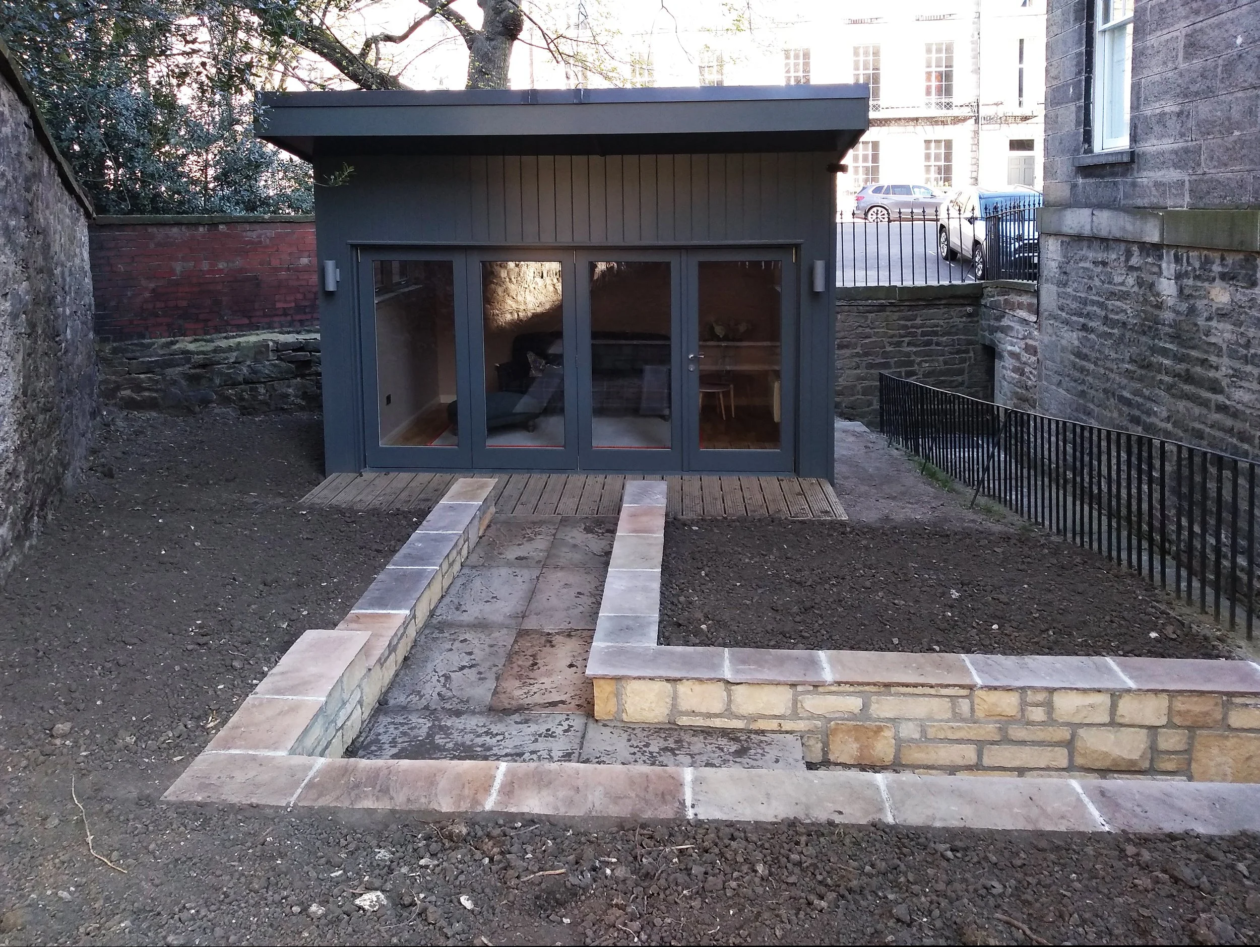 A new garden office surrounded by bare planting beds.