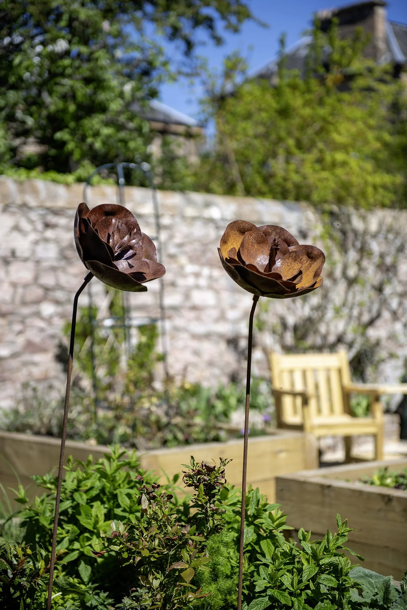 Garden ornaments: two large metal flowers accent this raised bed area.