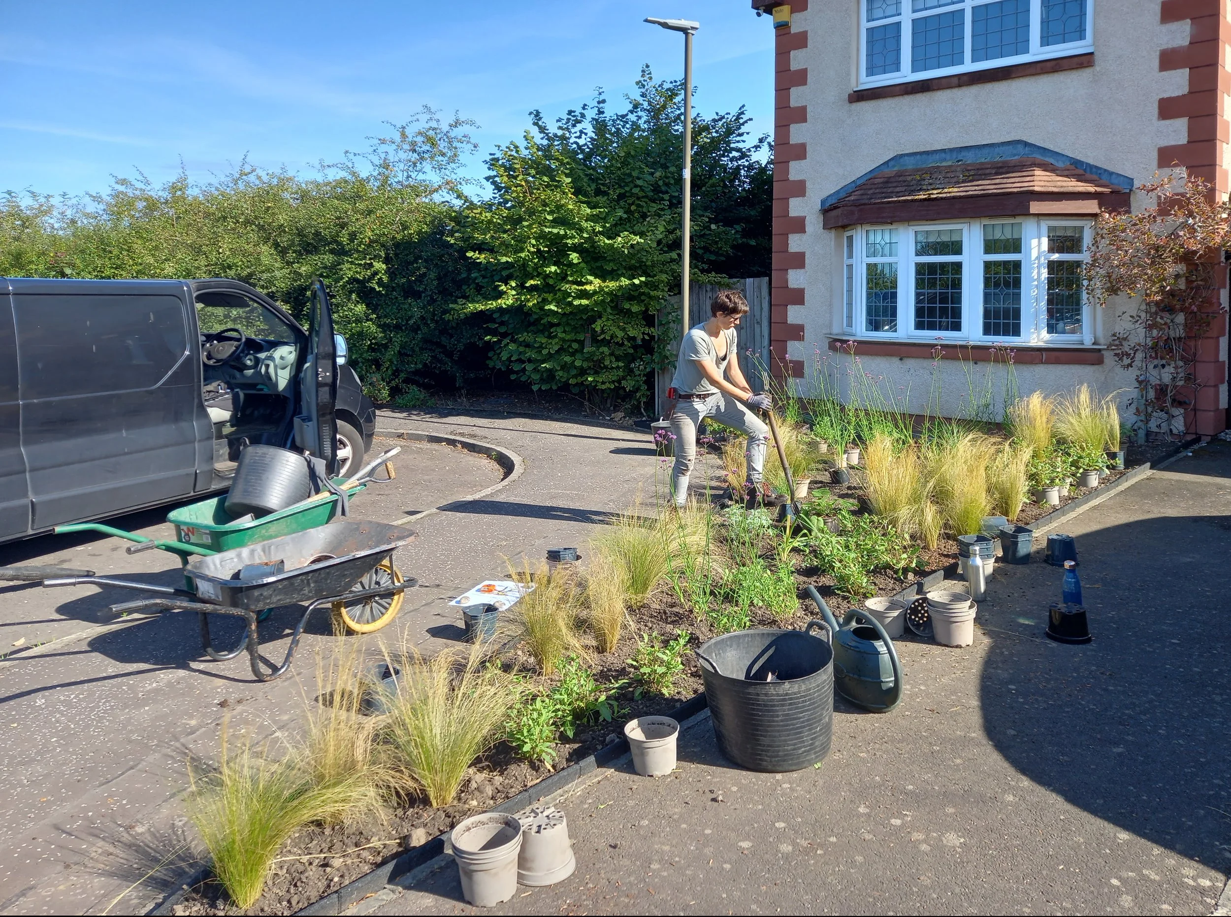A newly planted bed with planting tools, and empty plant pots scattered around.