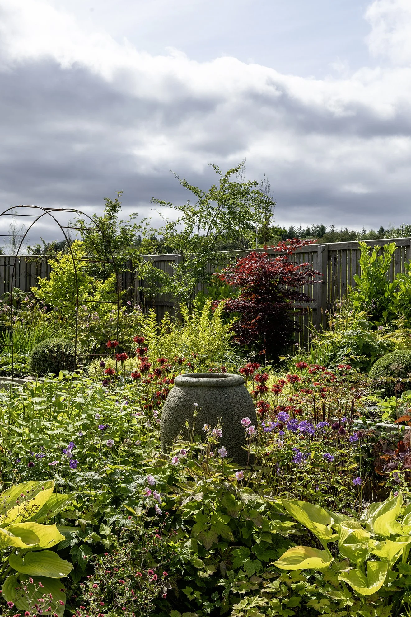 A beautiful, foliage filled garden with a central urn 