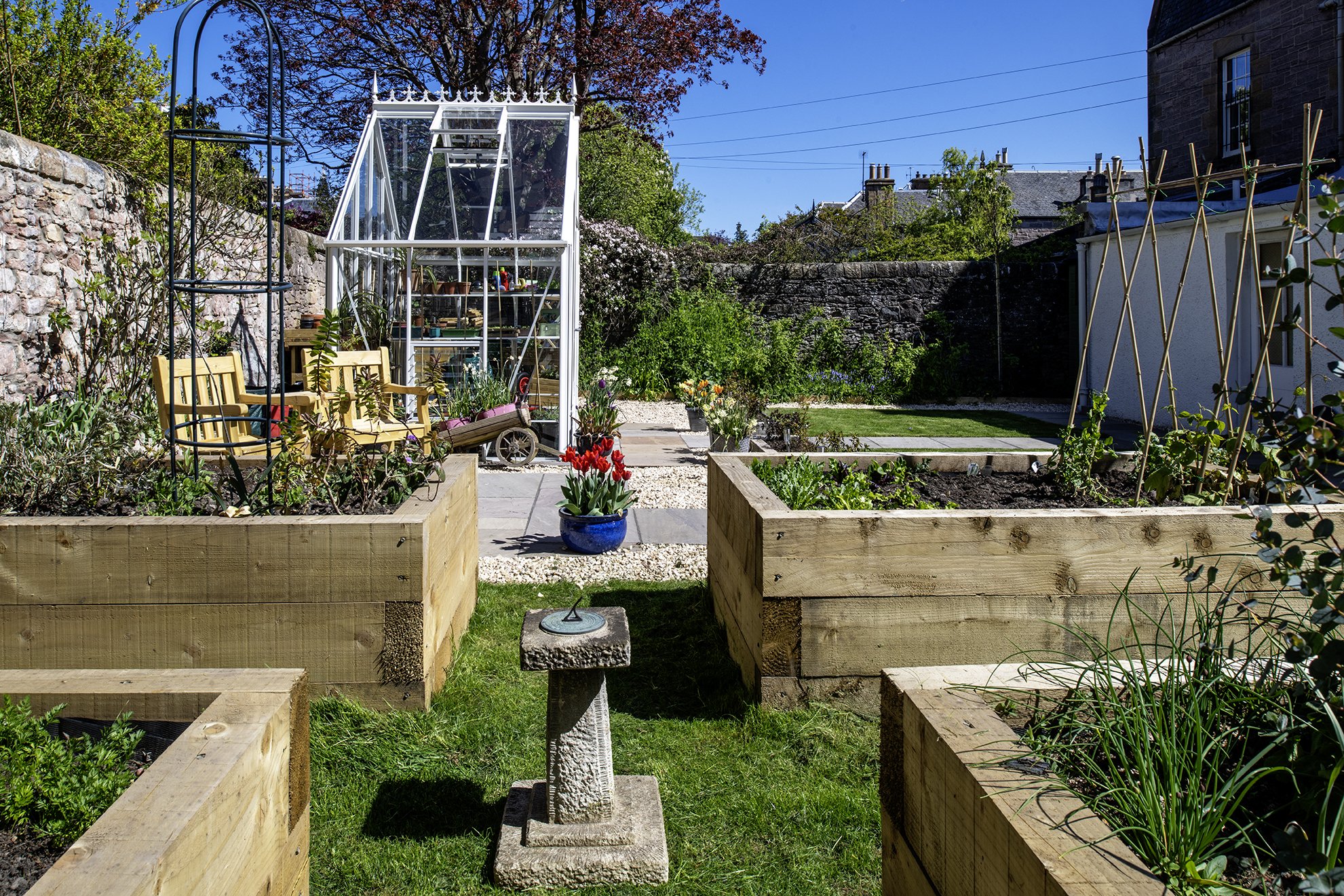 A sundial makes a focal point in the middle of these raised beds in a kitchen garden.