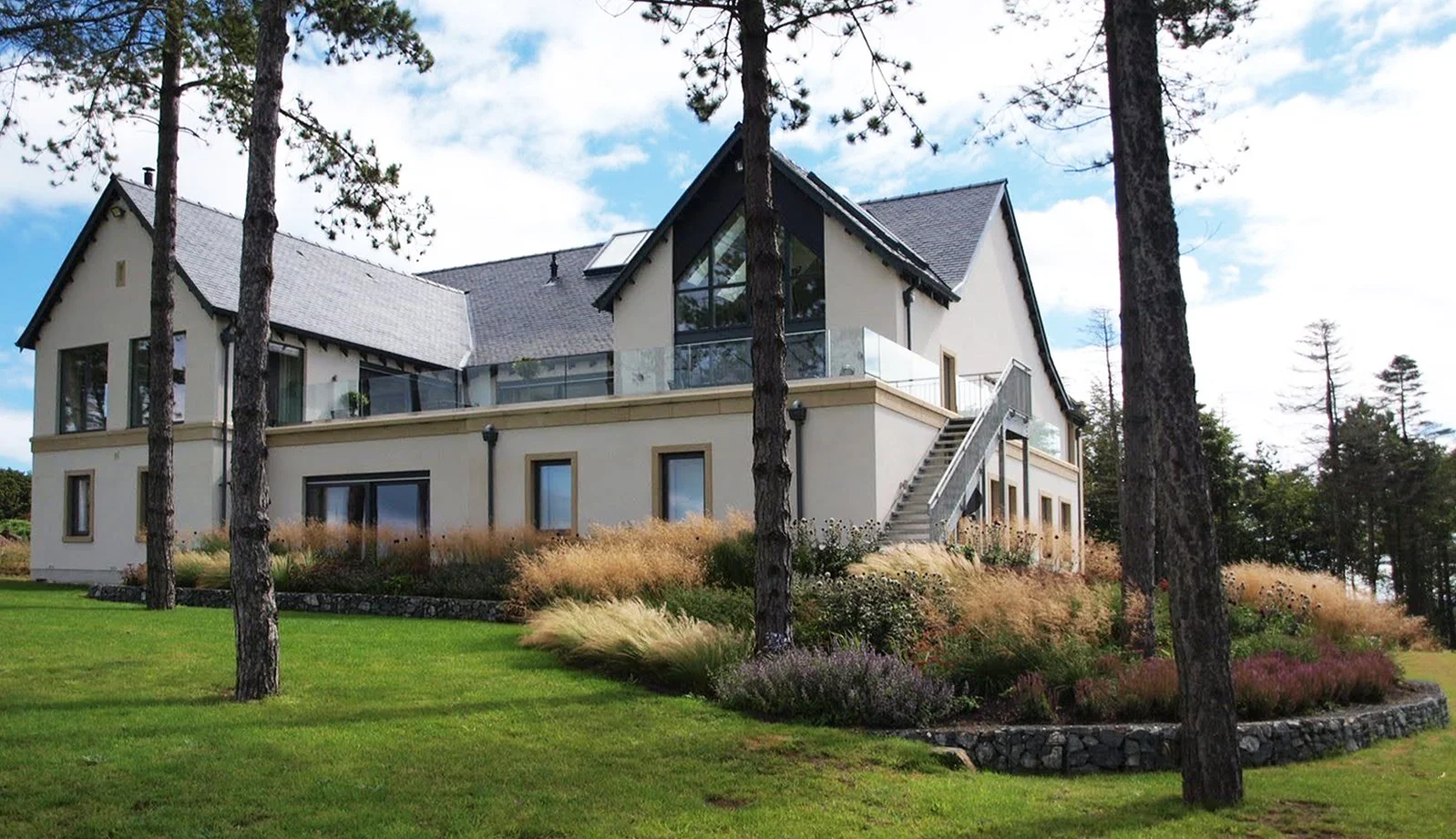 Grasses blowing in the wind in a planting bed outside a house.