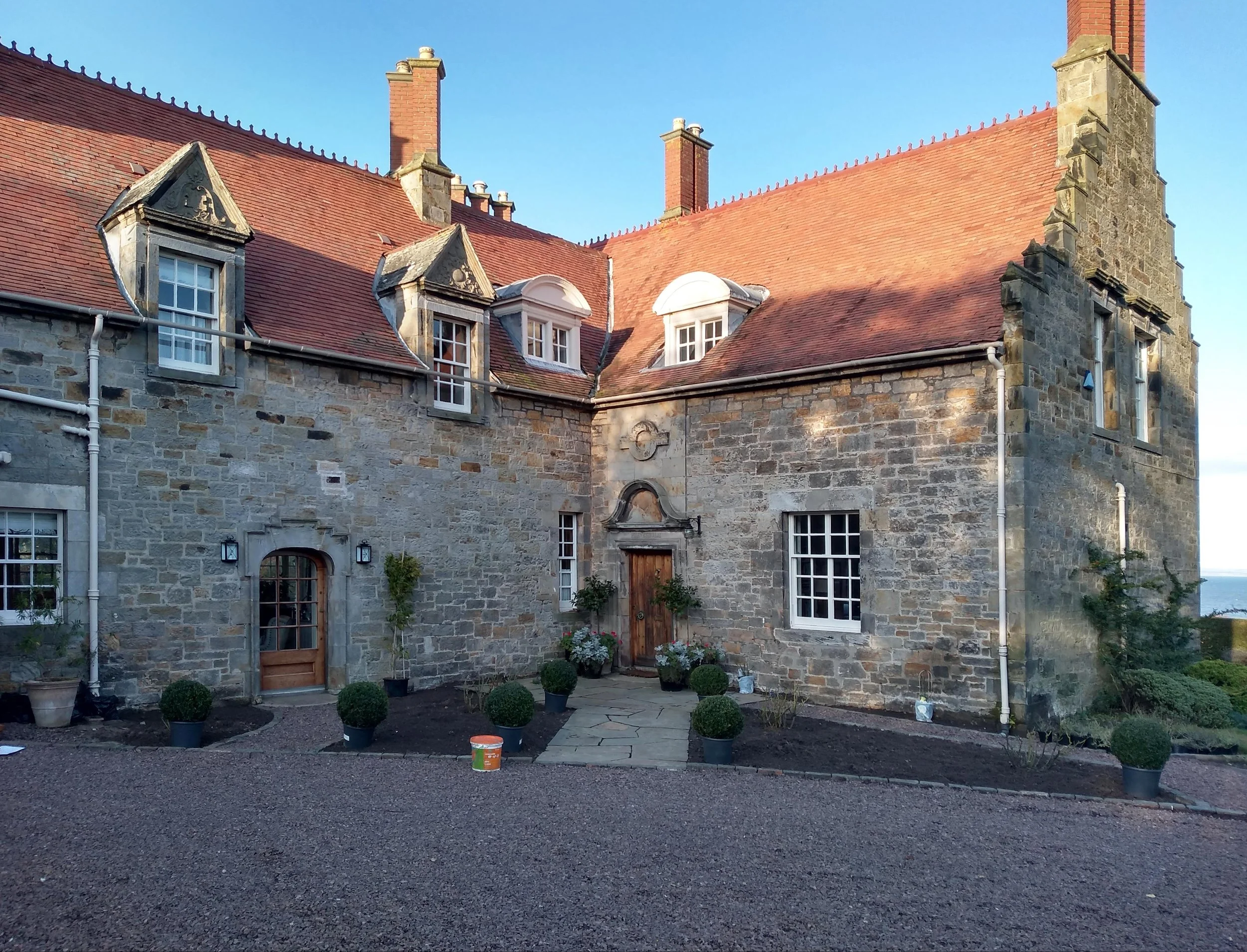 Bare planting beds in front of the facade of an old historic home.