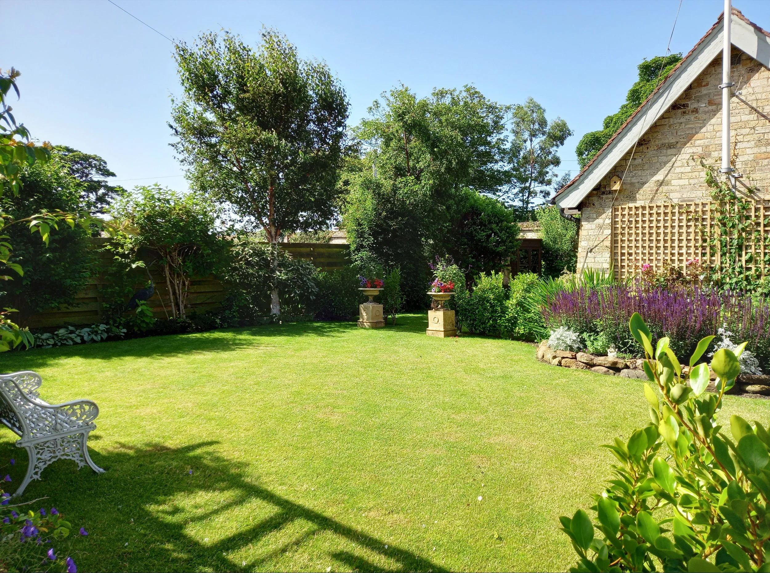 large green lawn surrounded by flowers and shrubs.