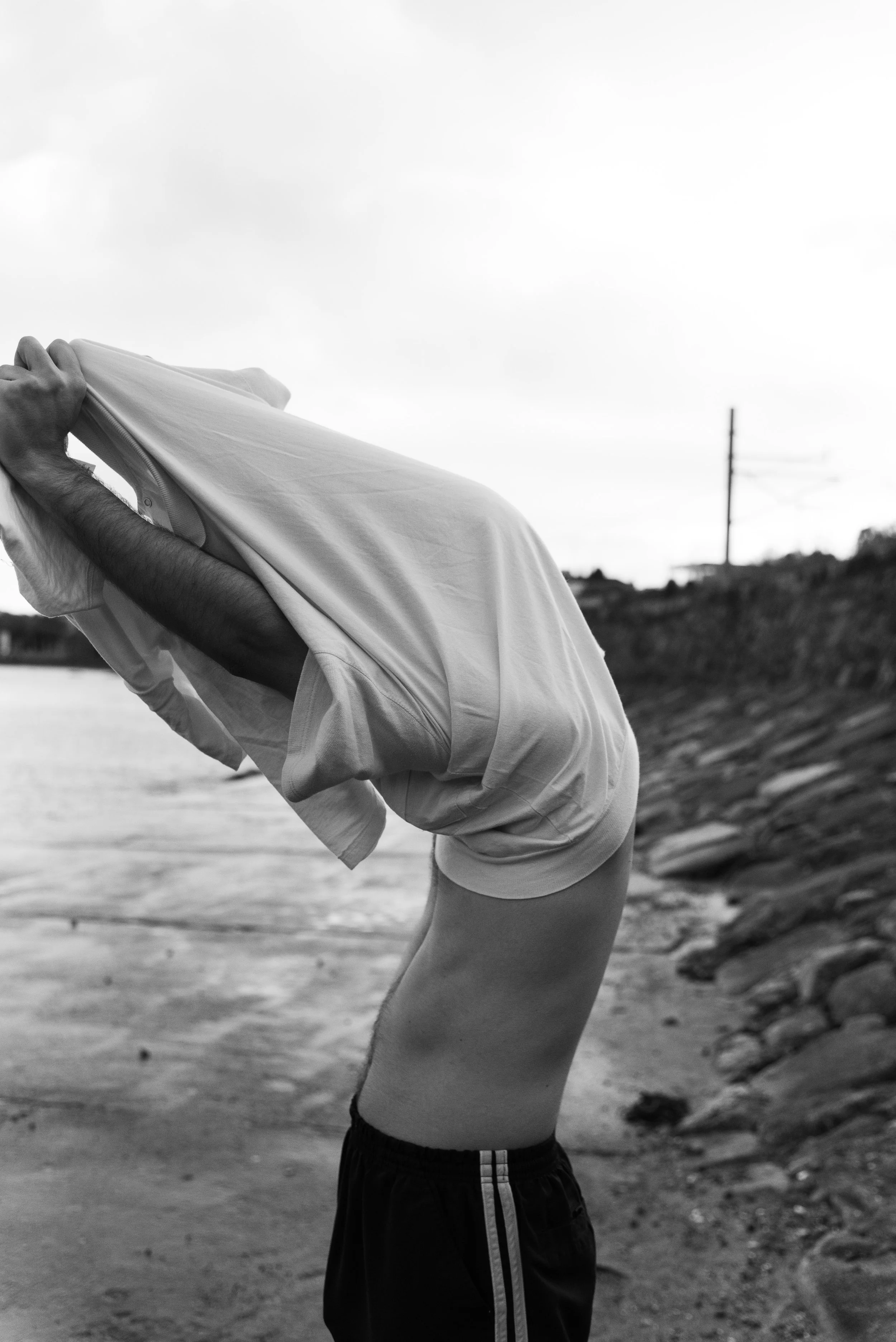 Boy taking shirt off at the beach.