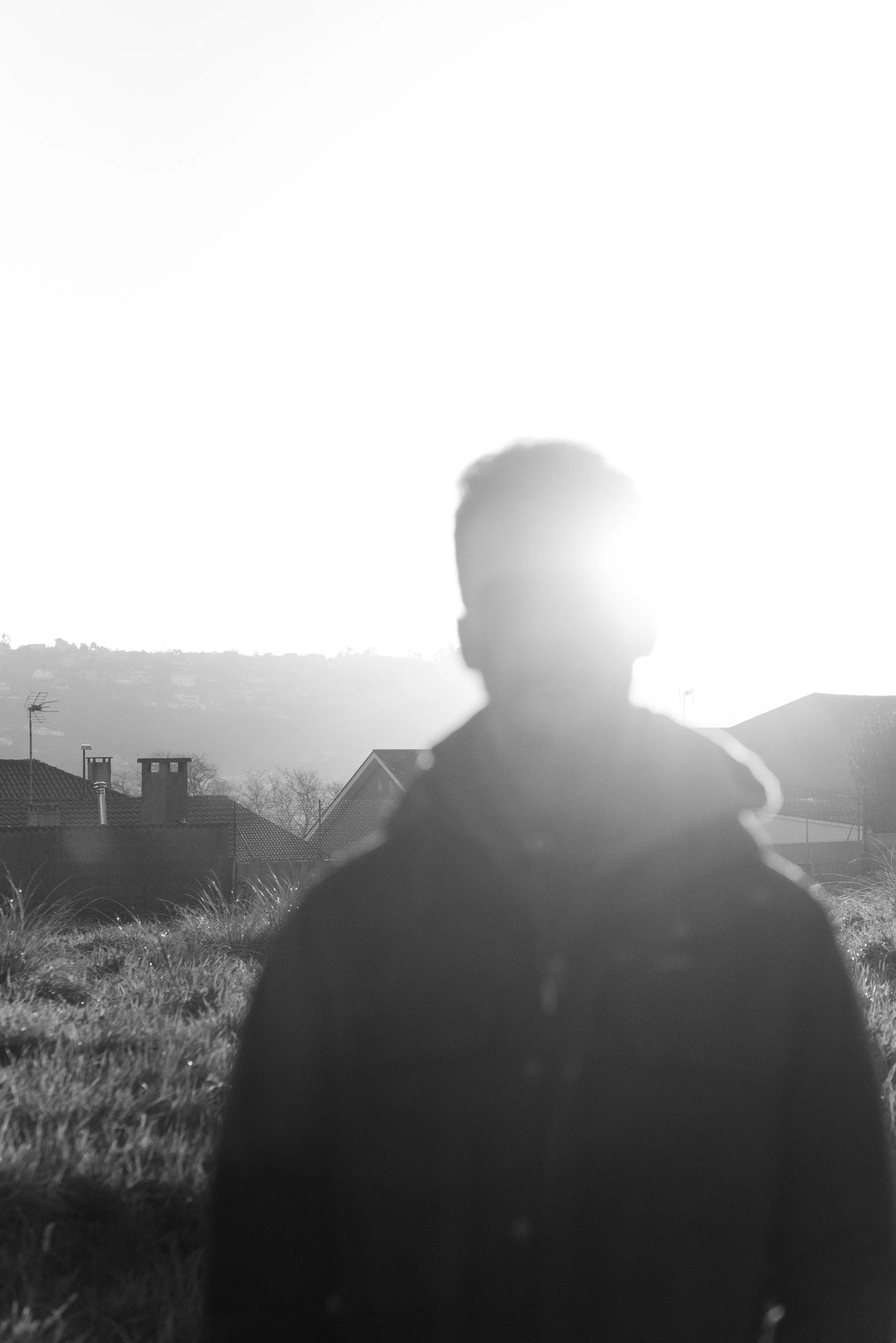 Portrait of boy in field with sun obstructing view of face.