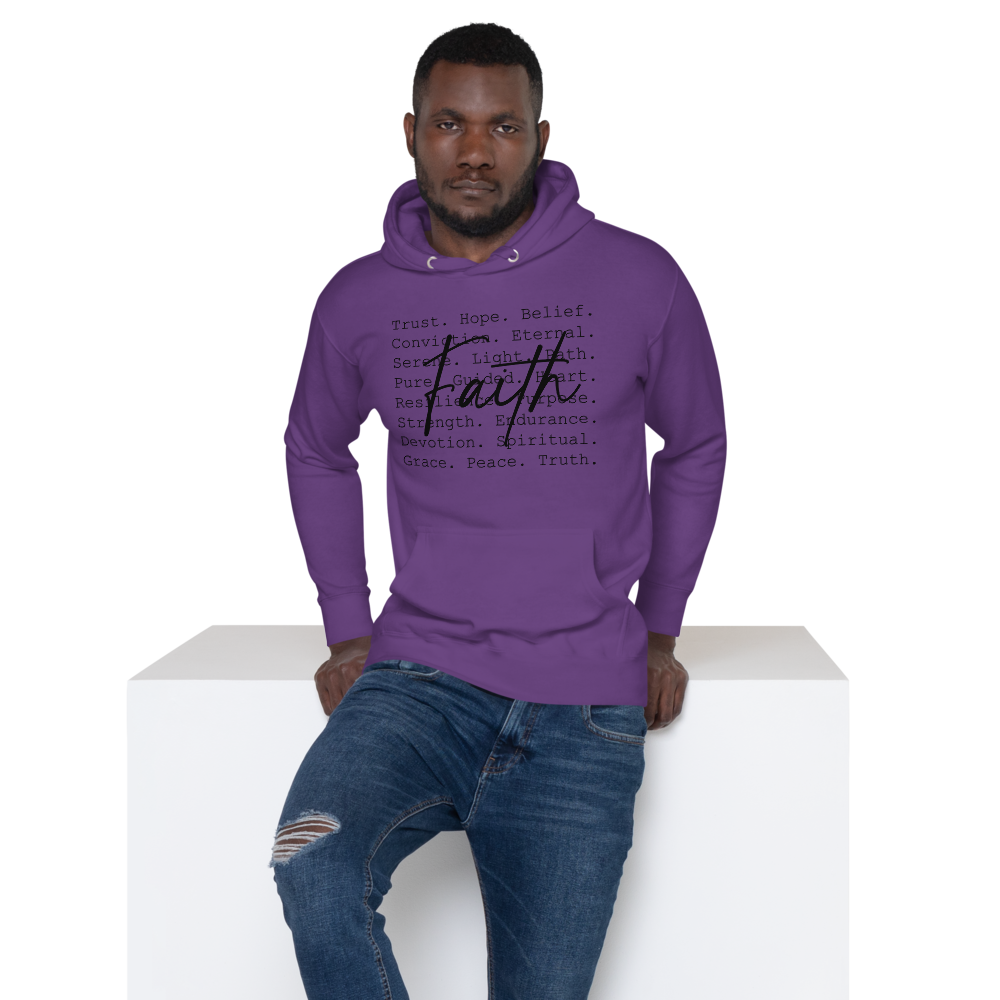 A man wearing a purple hoodie with black and purple text, and blue ripped jeans, leaning against a white surface.