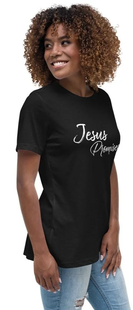 A woman with curly hair wearing a black T-shirt that says 'Jesus Promises' and light blue jeans.