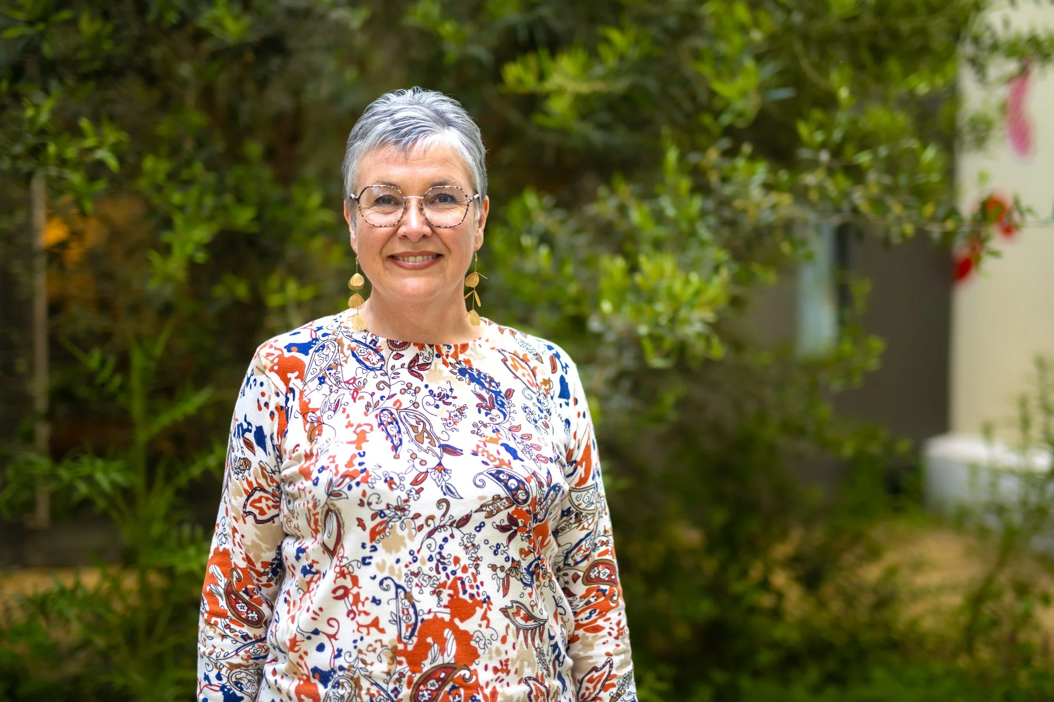 Corinne se tient devant un fond de végétation verdoyante.