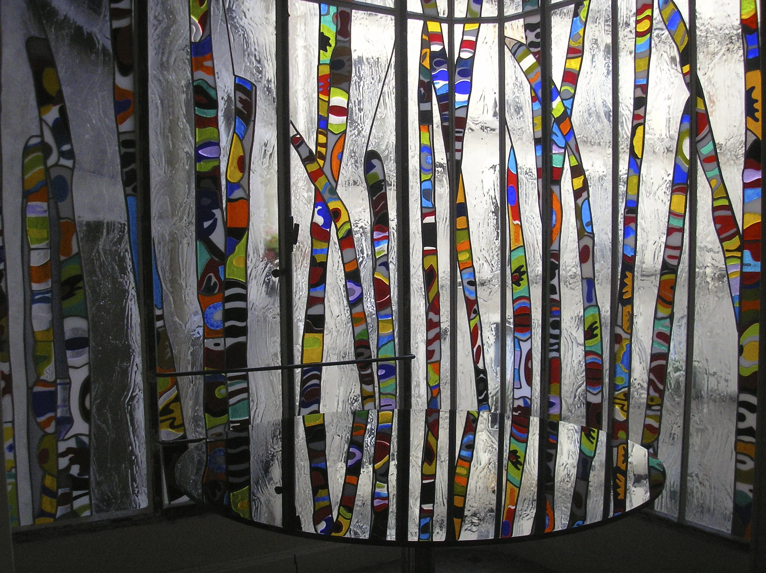 Vitrail coloré inspiré de la nature couvrant une baie vitrée incurvée