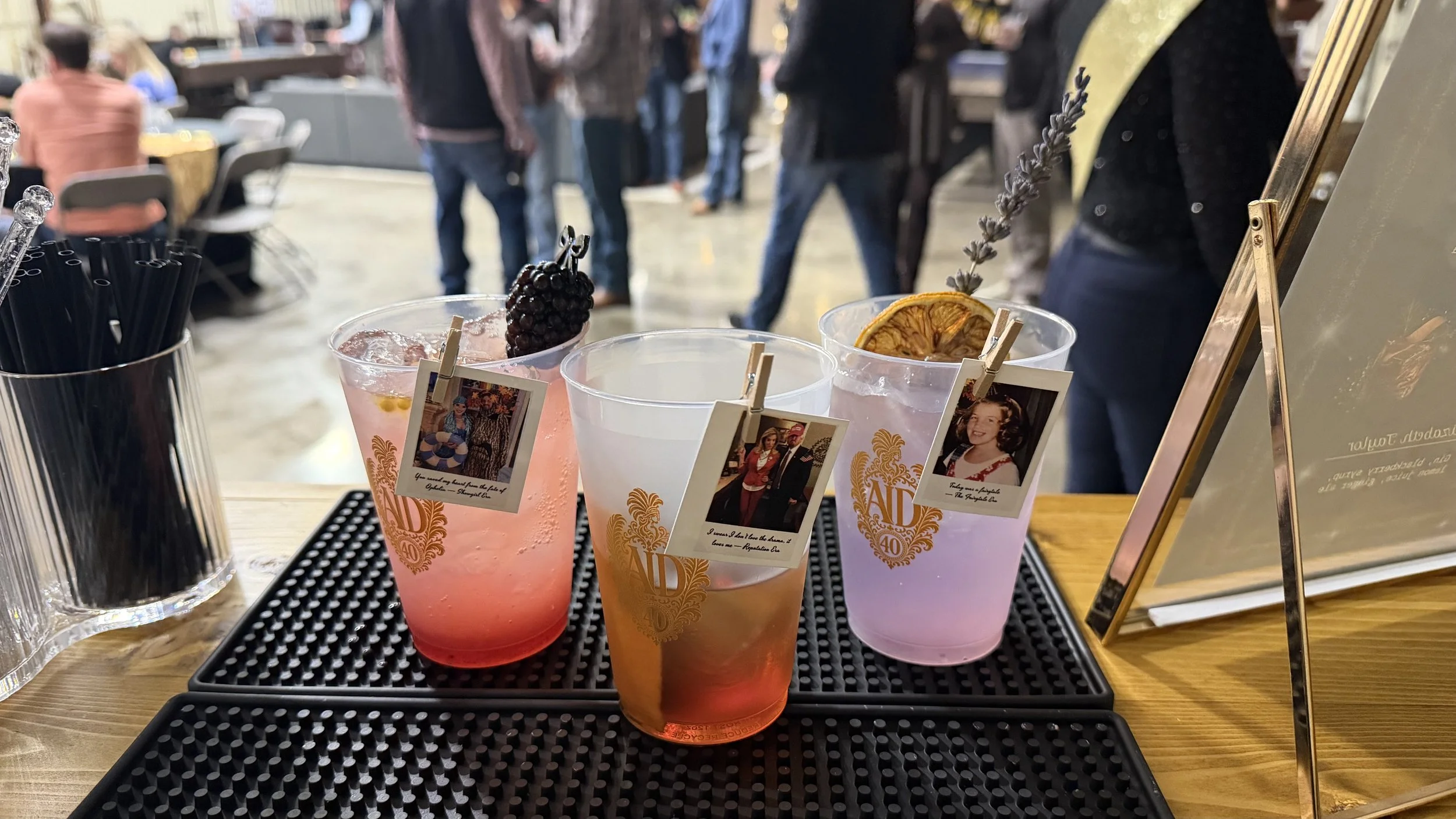 Colorful signature cocktails garnished with blackberries, dried citrus, and lavender at a 40th birthday celebration bar