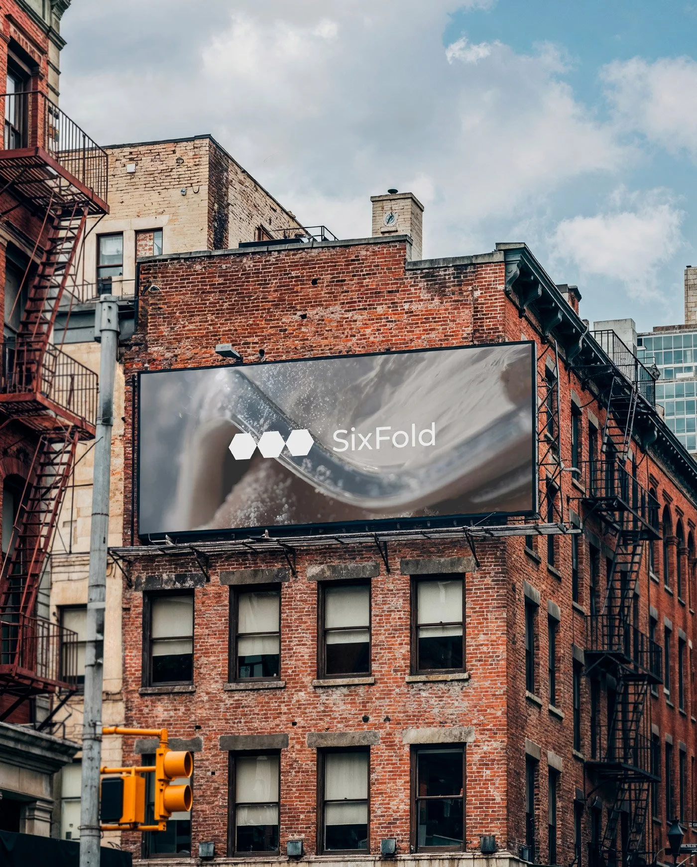 Sixfold sports brand identity applied to a large-scale outdoor billboard on a red-brick building, showcasing contemporary logo design and urban advertising.