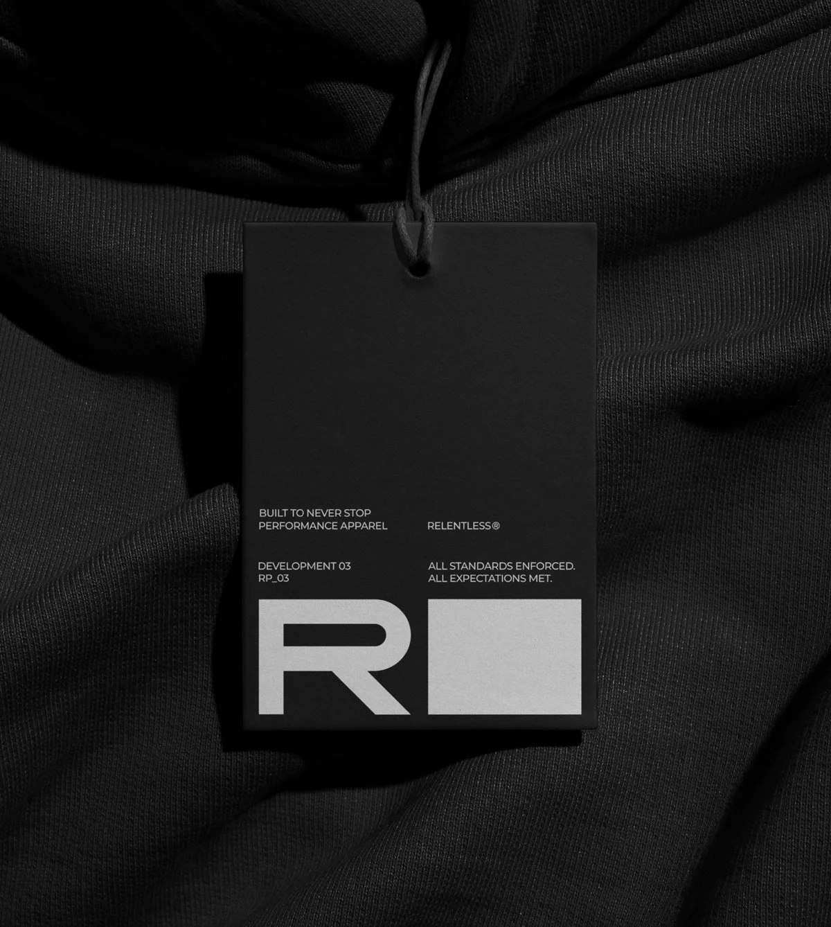 Relentless apparel tag mock-up using institutional typography, modular layout, and protocol-style copy to reinforce a standards-driven identity.