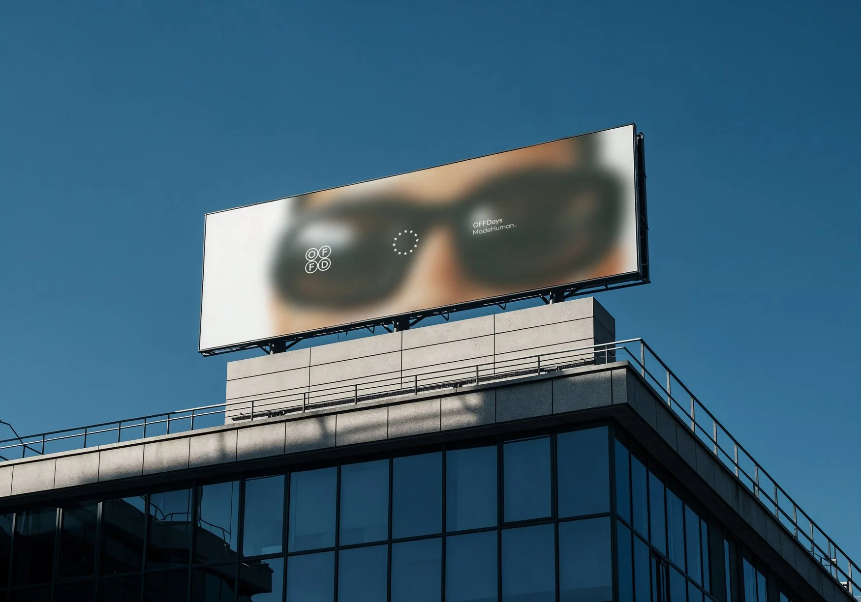 OFFDays lifestyle brand identity applied to a large rooftop billboard, combining the OFFD monogram, symbol ring and MadeHuman signature over blurred photography to express a calm, contemporary and typography-led brand presence.