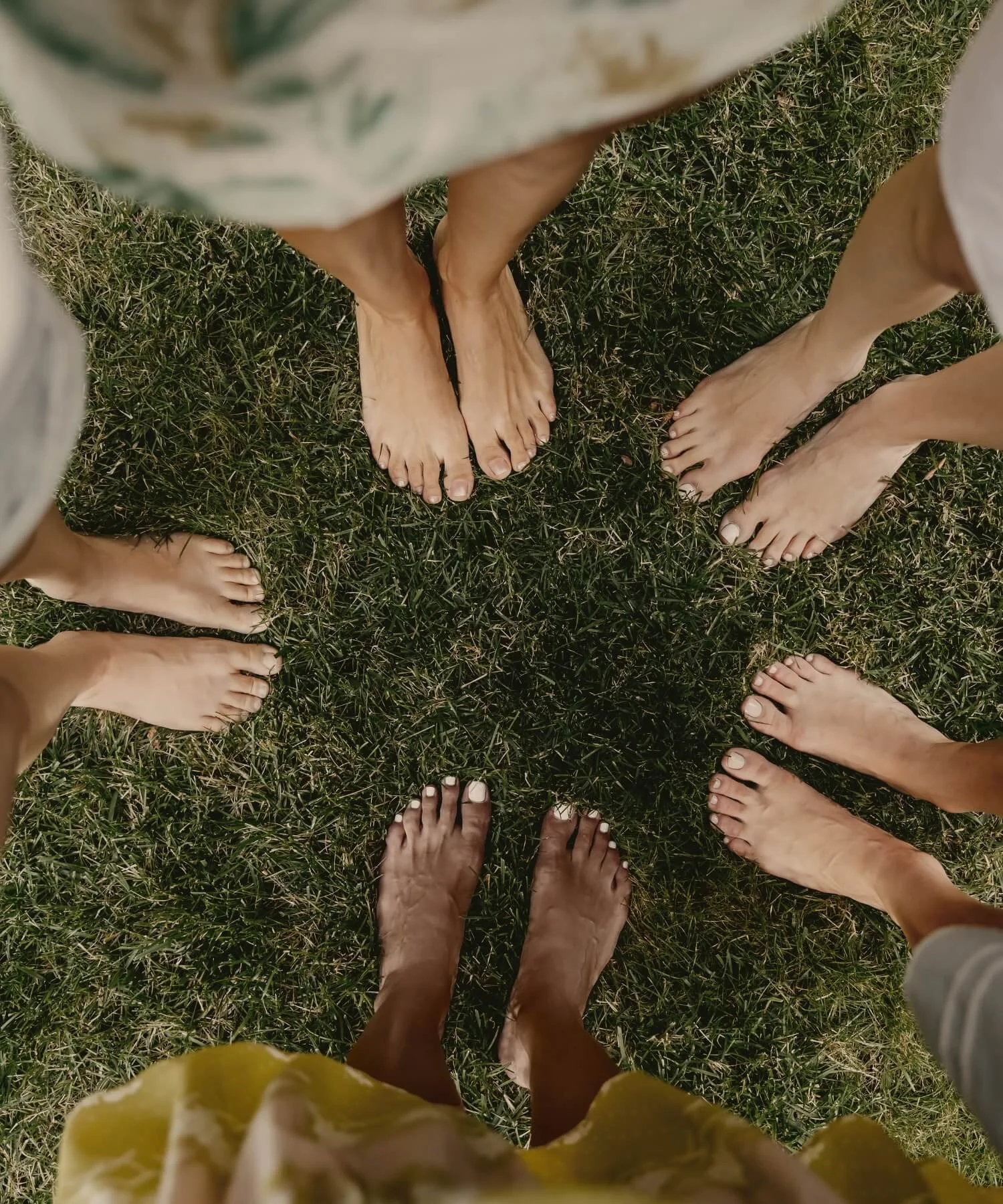 Women standing barefoot in a circle on grass, representing connection, community support, and a safe therapeutic space for counseling services