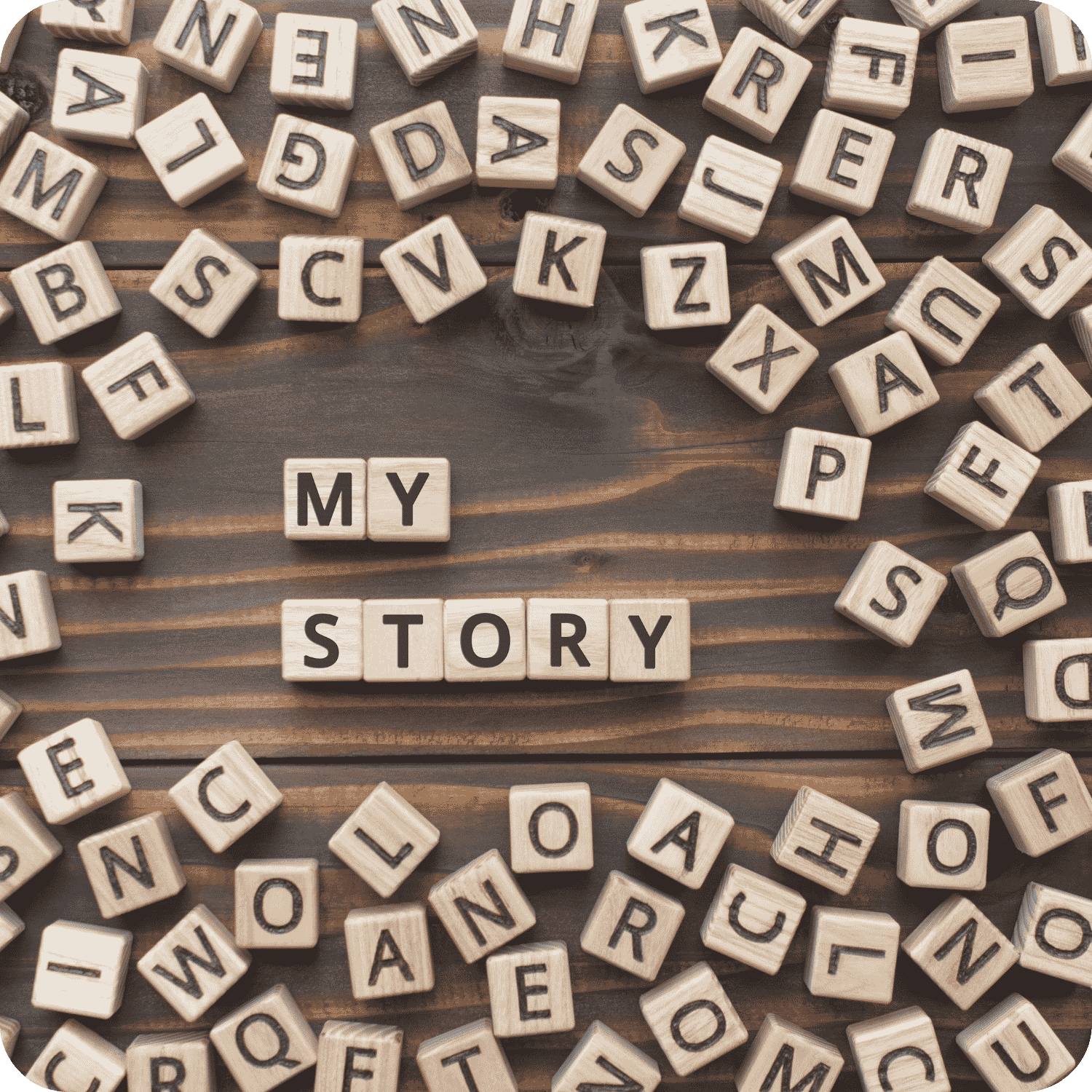 Wooden letter tiles spelling “MY STORY” surrounded by scattered letters on a dark wooden surface