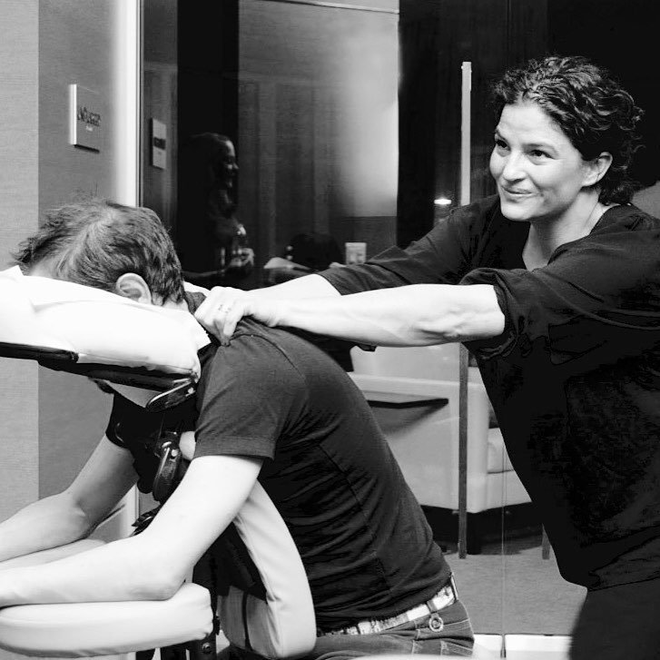 Woman pulling back a young man in a wheelchair with his head resting on a pillow, in a healthcare setting.