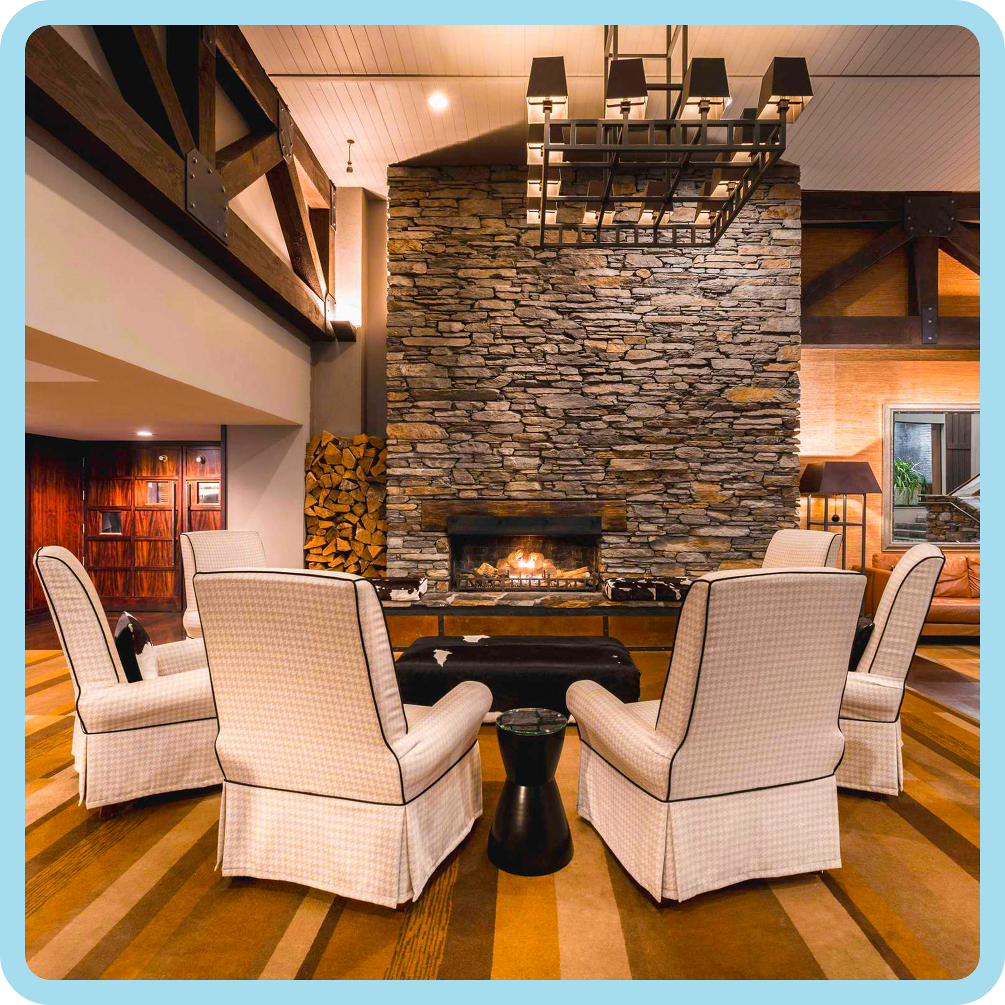 Living room with stone fireplace, beige upholstered chairs, and a modern black side table.
