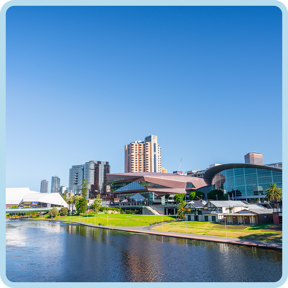 City skyline with modern skyscrapers and waterfront park under clear blue sky.