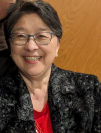 Carol, a Japanese American woman with short hair and glasses,  smiles for the camera
