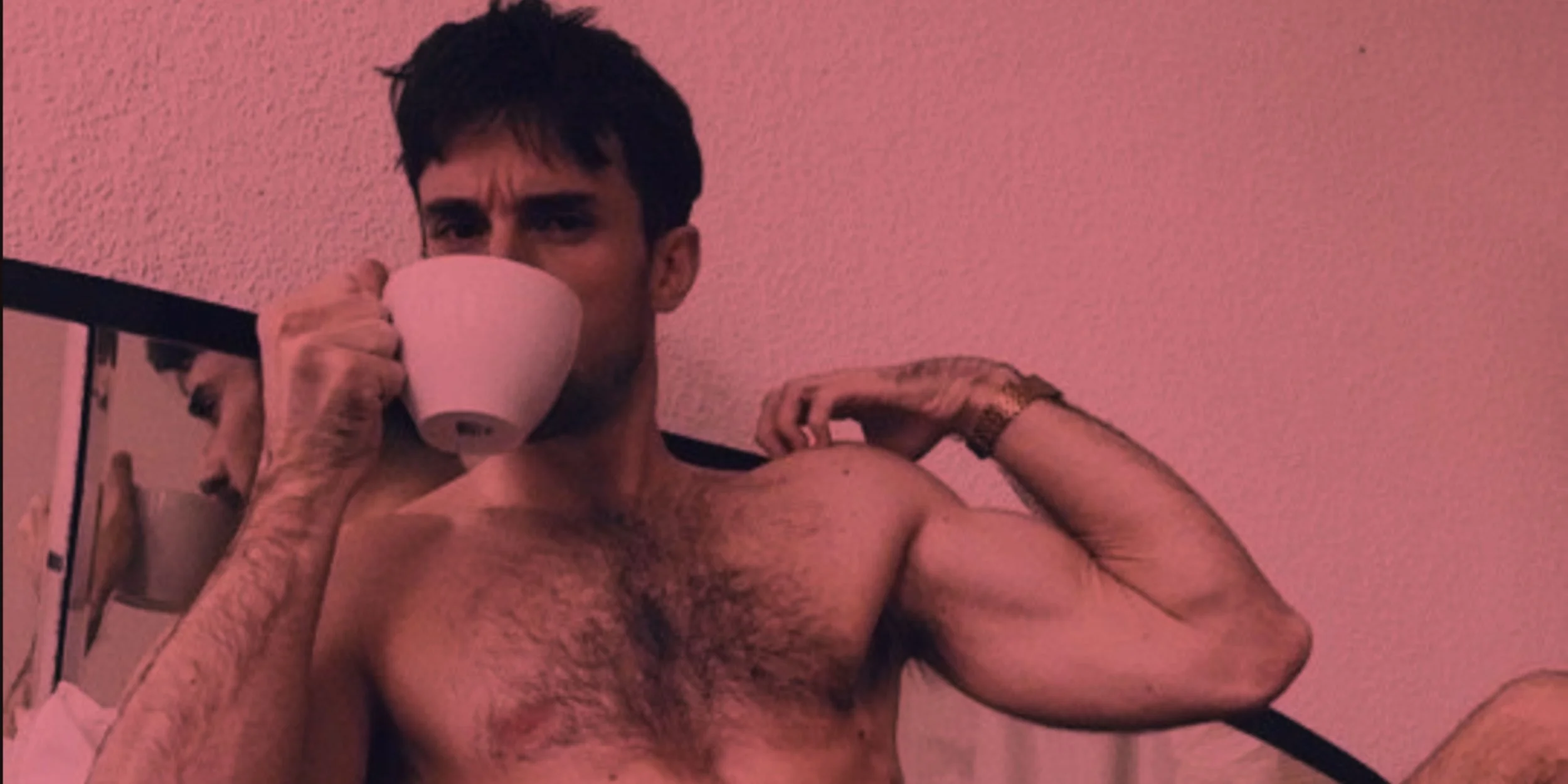 Young shirtless man with short black hair looking at the camera against a plain background.