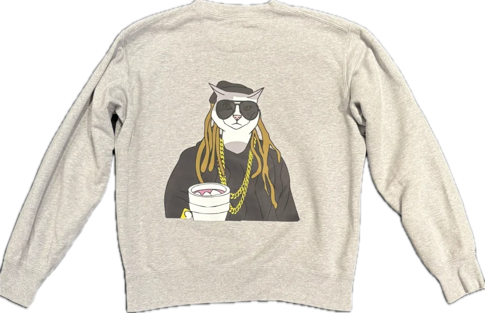 Gray sweatshirt with a cartoon illustration of a cool cat wearing sunglasses, gold chains, and holding a white cup with a beverage.