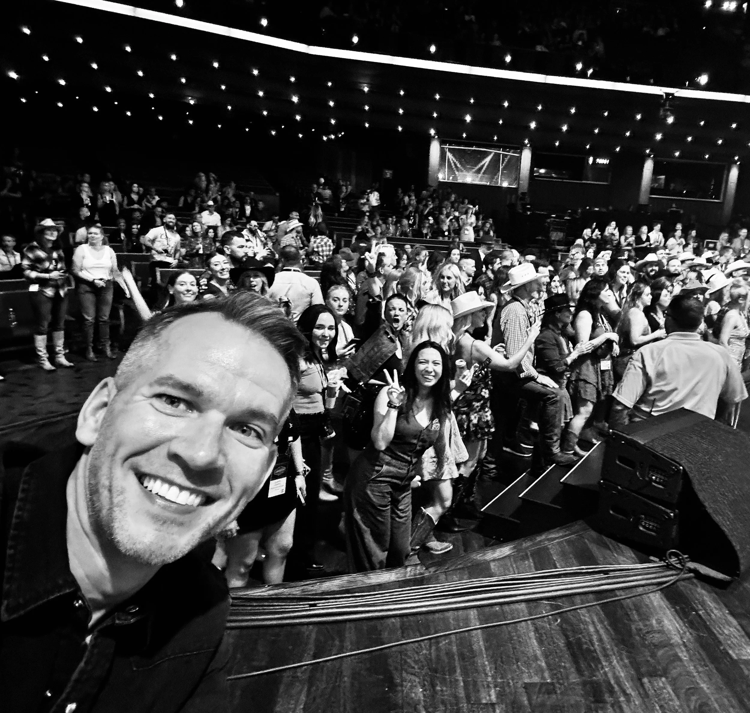 JJ Creegan taking a selfie on stage in front of a large crowd during a leadership event.