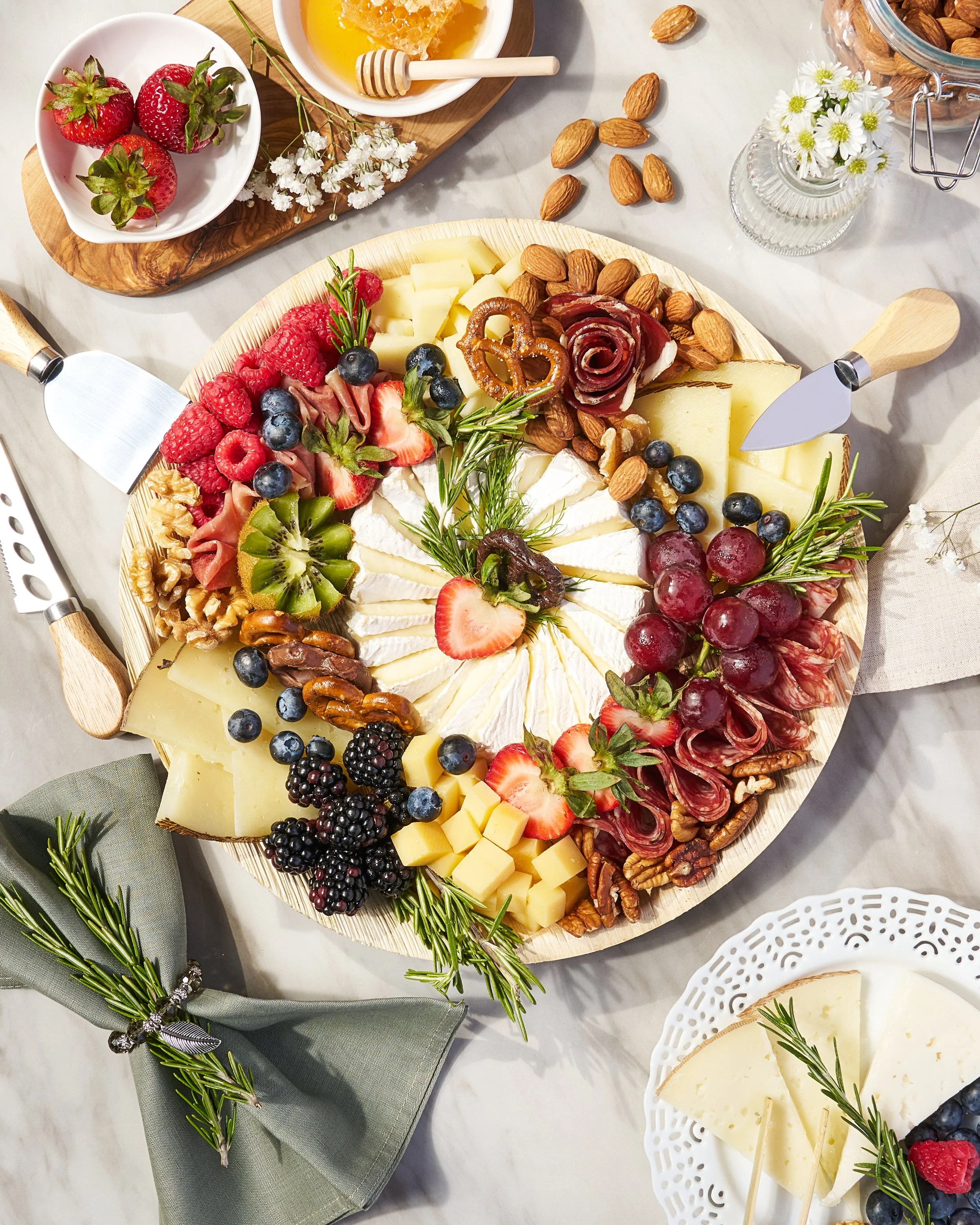 Bright, lifestyle food photography showcasing an artfully styled charcuterie board with cheeses, cured meats, fresh fruit, and herbs—perfect for culinary branding, menus, and social media.