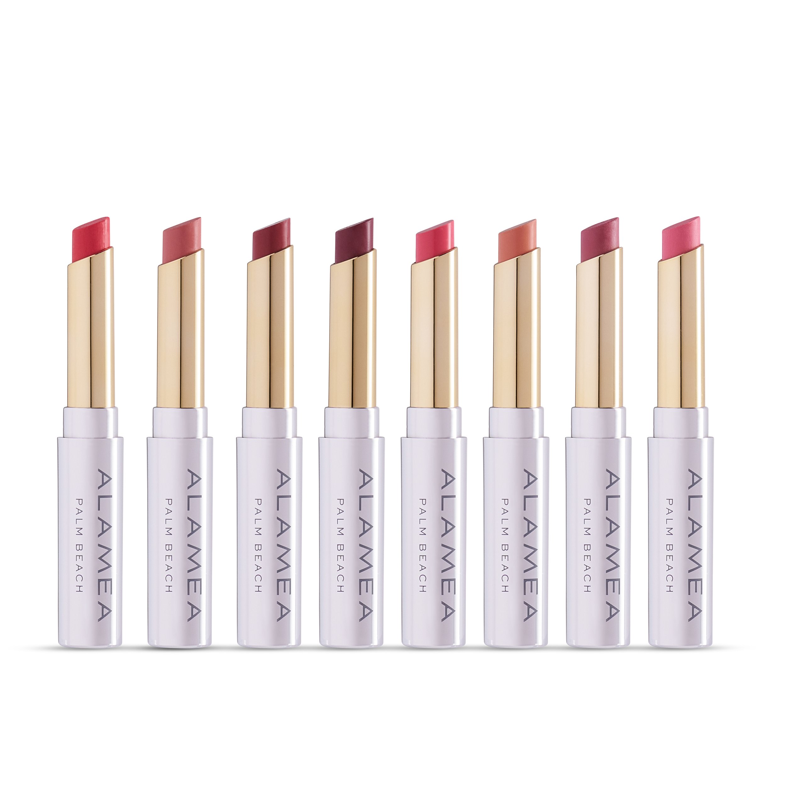 Eight lipsticks with sleek, white and gold packaging standing in a row, featuring various shades from pink to nude.