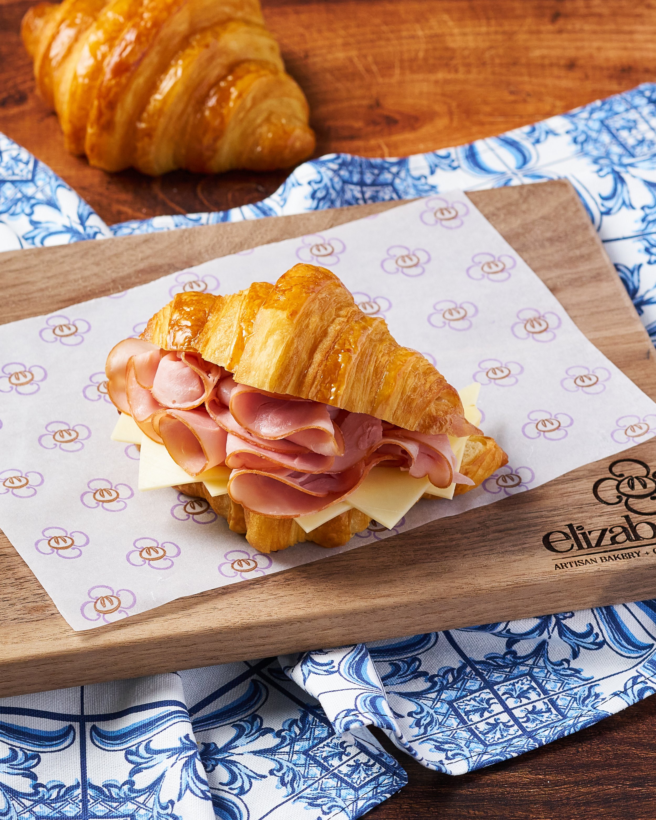 A ham and cheese croissant is laid nicely on a cutting board in warm lighting