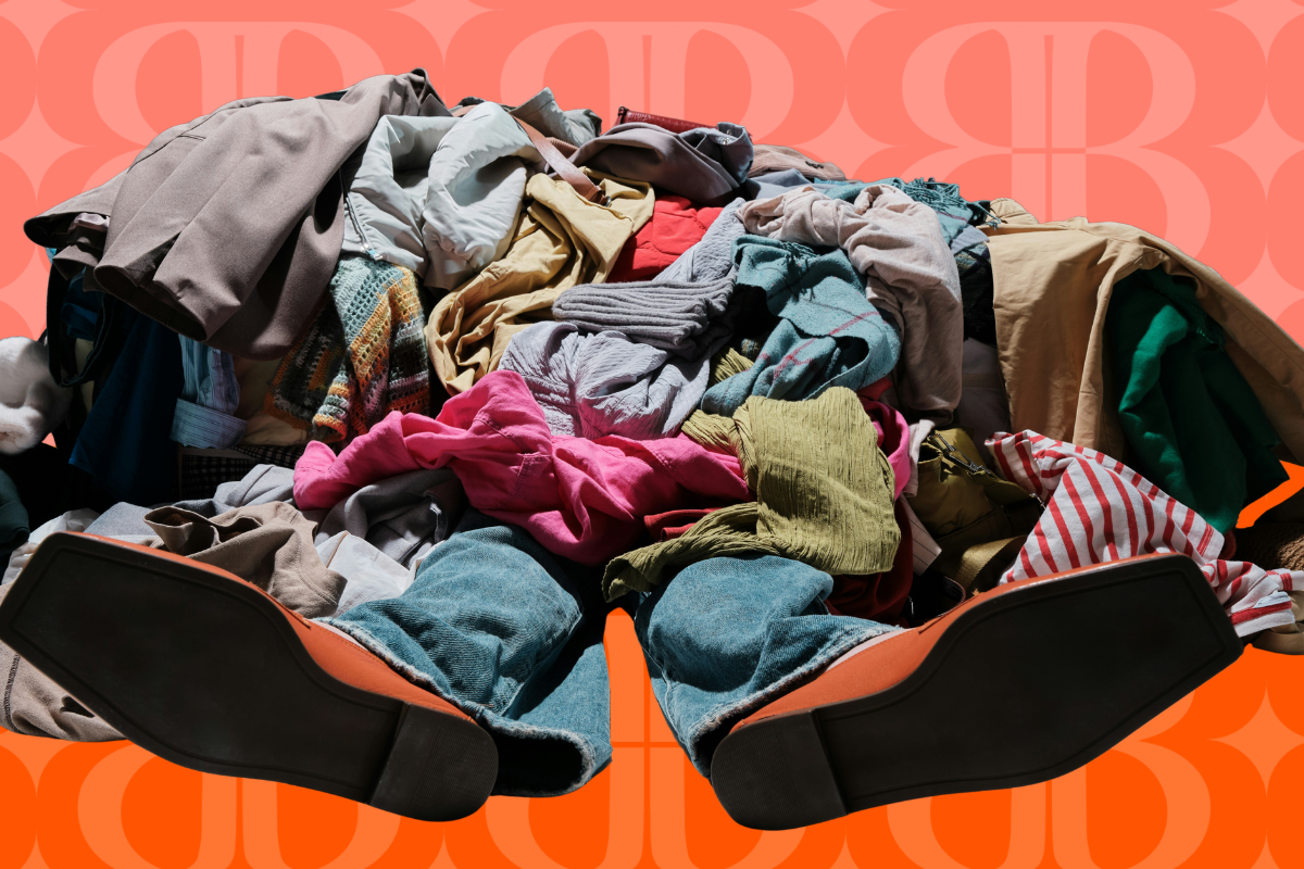A person sitting in an orange chair with their legs stretched out, surrounded by a large pile of various clothes.