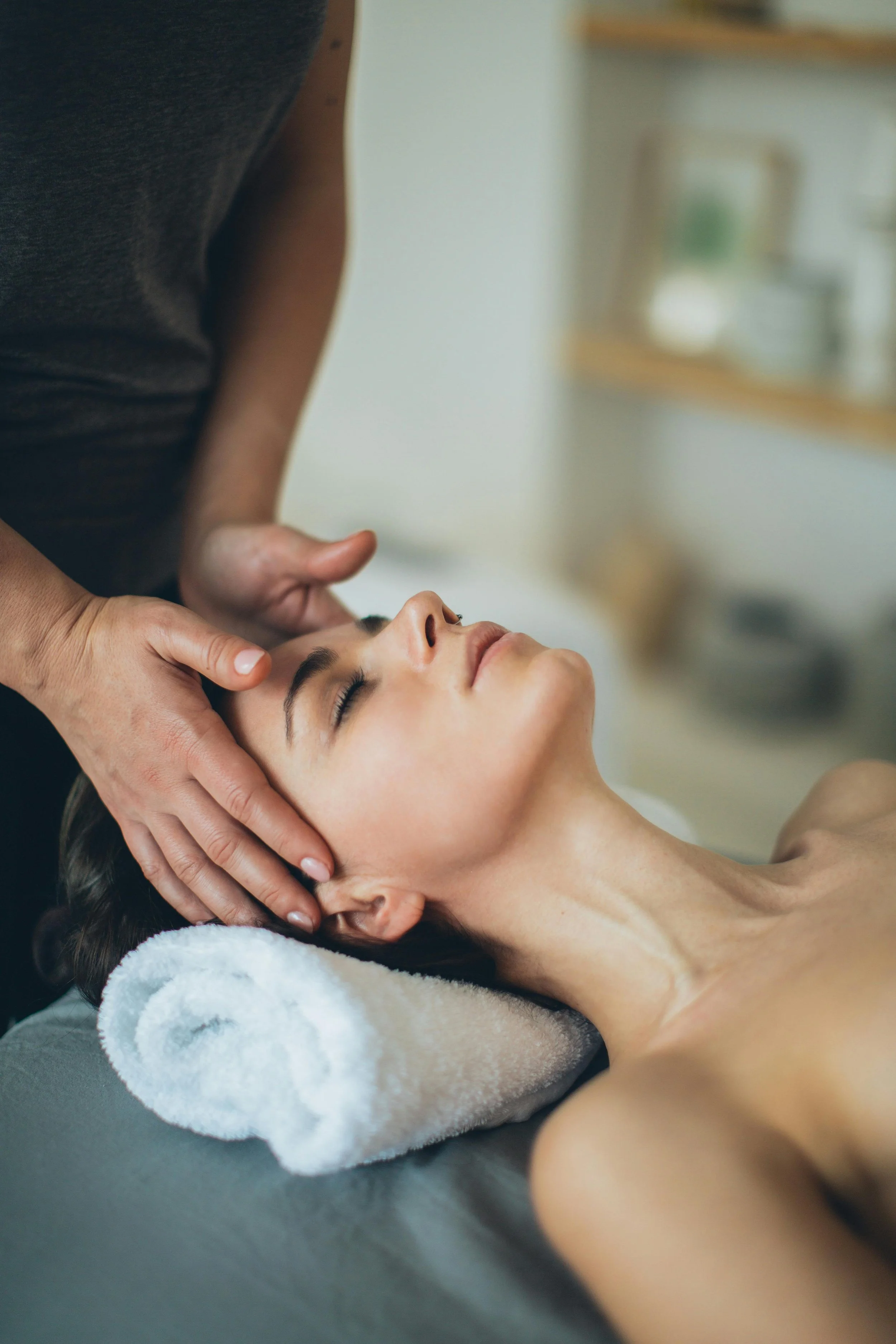 Woman receiving a facial massage from a therapist in a spa setting.