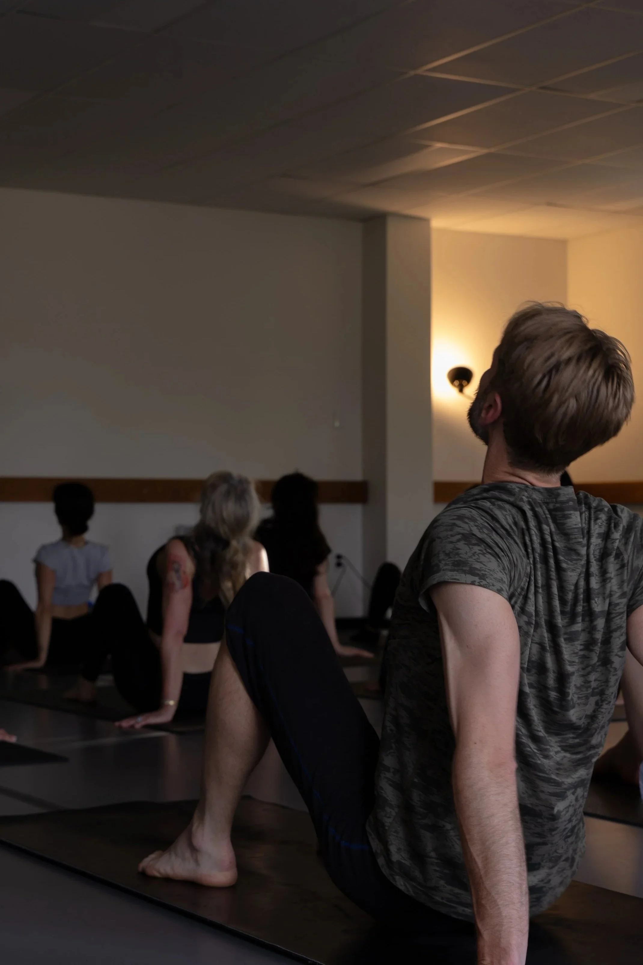 People practicing pilates poses indoors near windows.