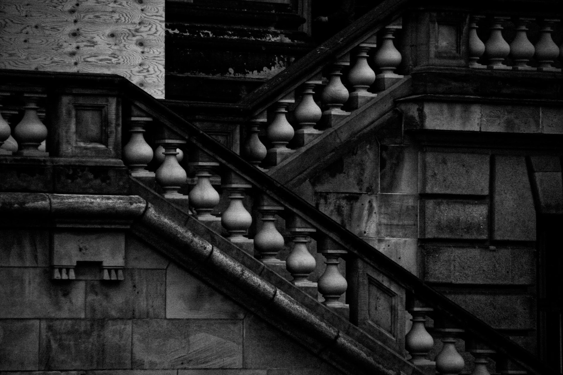 Black and white photo of a stone staircase with ornate balusters and carved stone details.