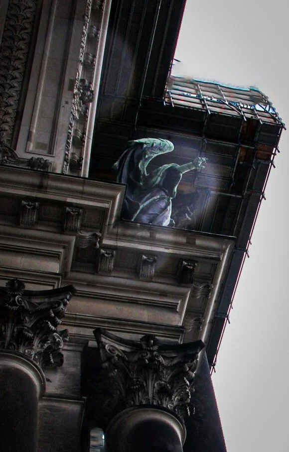 Looking up at the ornate facade of a historic building with classical architectural details, including carved columns and decorative moldings, from a low-angle perspective.