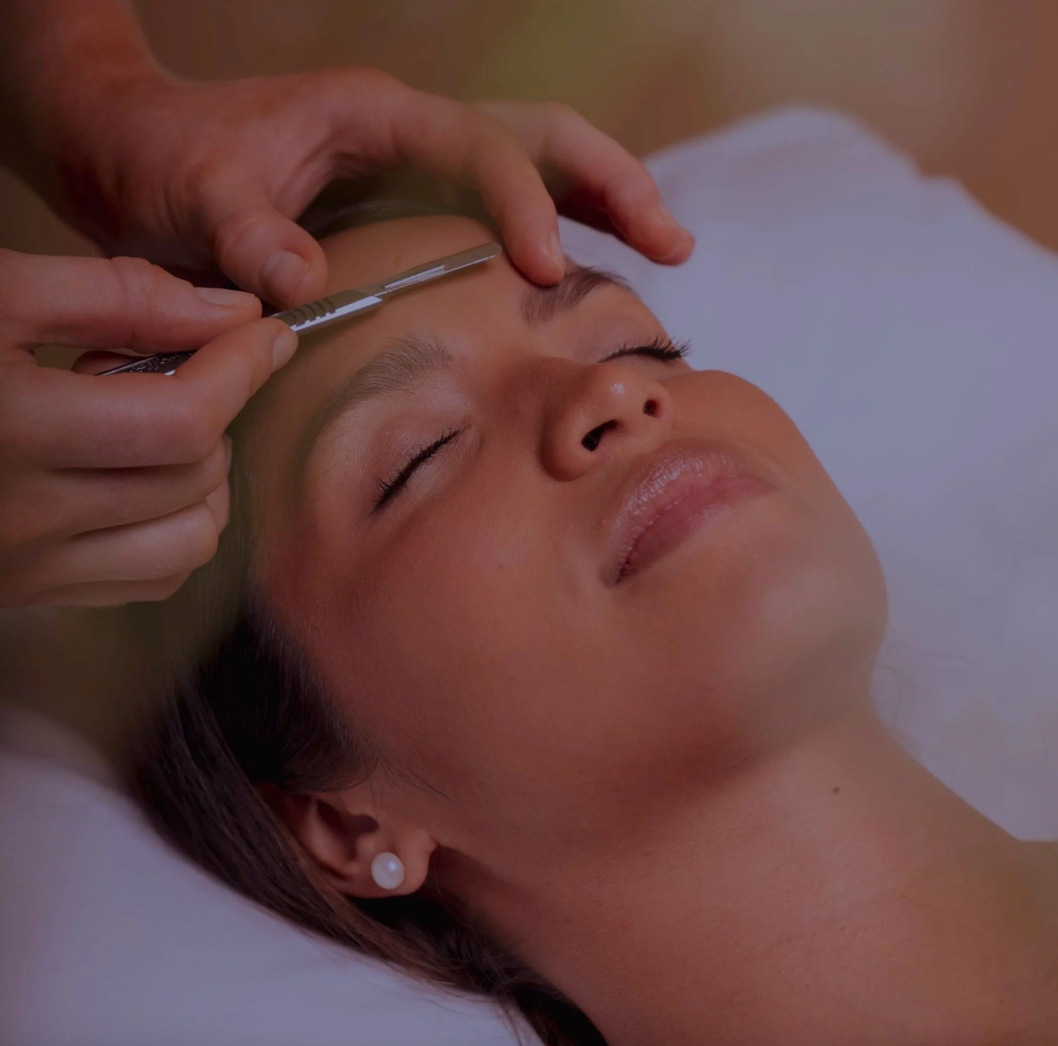 Woman receiving facial dermaplaning treatment with a scalpel.
