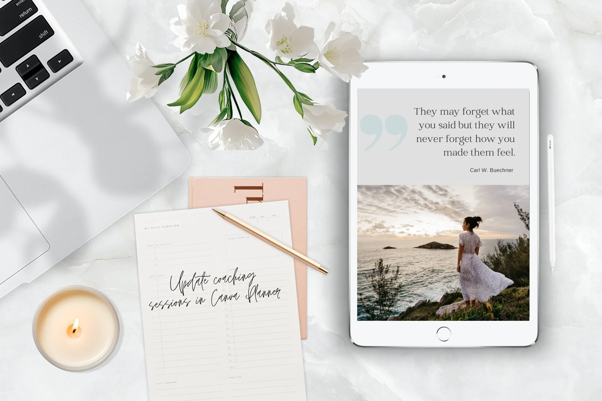 Top view of a workspace on a white marble surface, featuring a closed silver laptop, a bouquet of white flowers in a clear vase, a lit candle, a white paper with handwritten notes, a pink notebook, a gold pen, and a white tablet displaying a quote overlaid on a photo of a woman standing by the sea during sunset.
