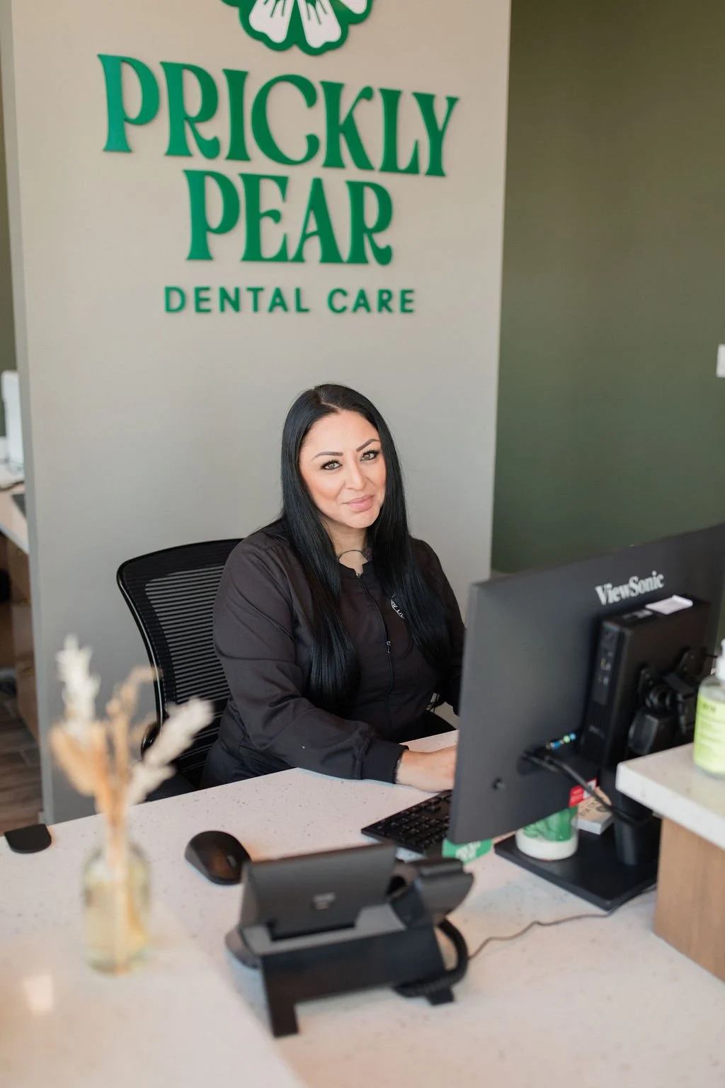 A photo of Jennifer sitting at the front desk in Prickly Pear Dental Care.